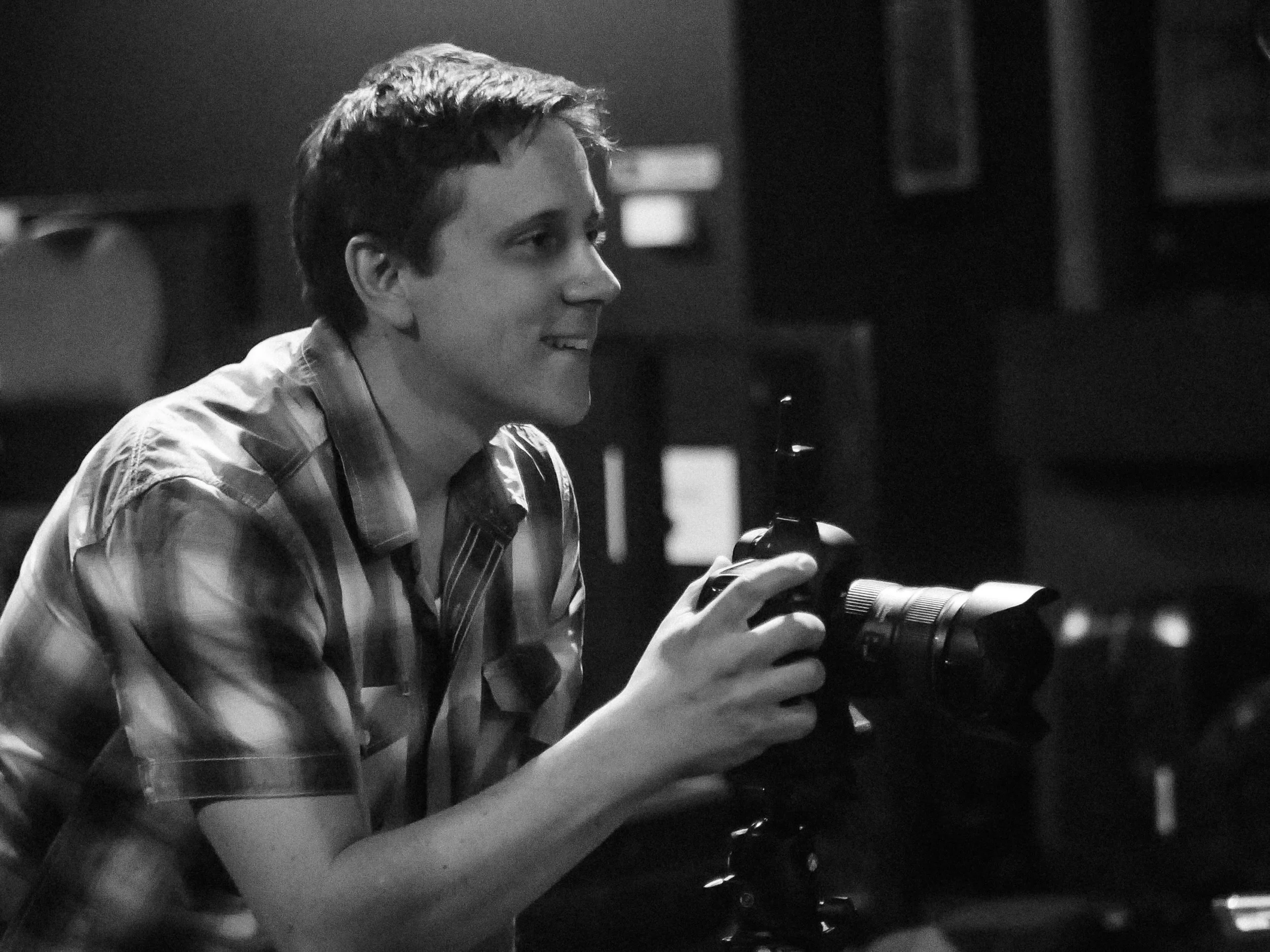 Ross Calia photographer, Melbourne. Black and white, holding a professional camera.