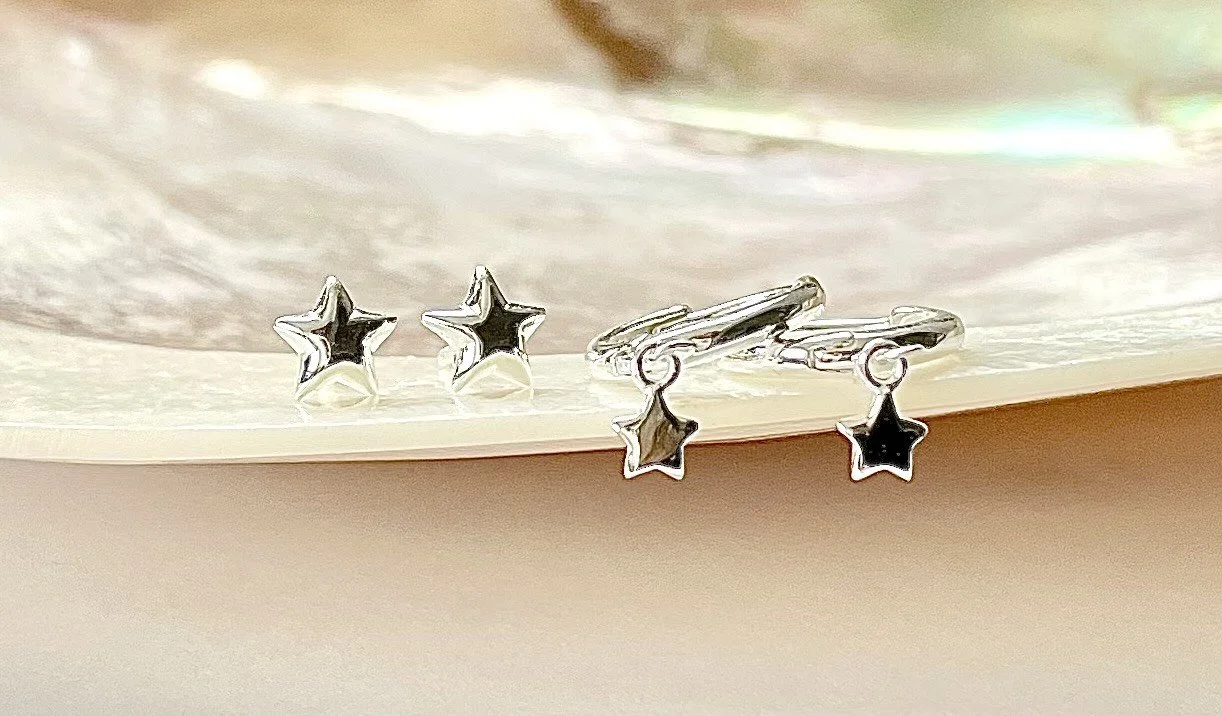 Silver star-shaped earrings on a shiny surface.