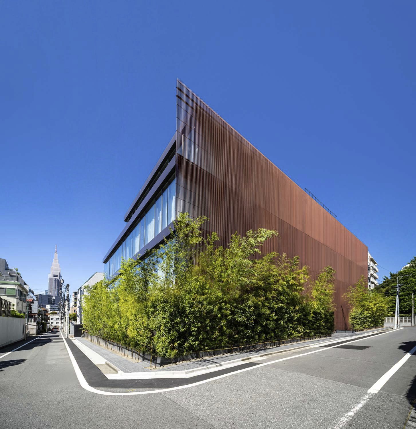 Kengo Kuma and Associates - The Kita - Westbank Corp. - Tokyo - Modern building with brown vertical lines, large windows, surrounded by green trees, city background High-end luxury housin