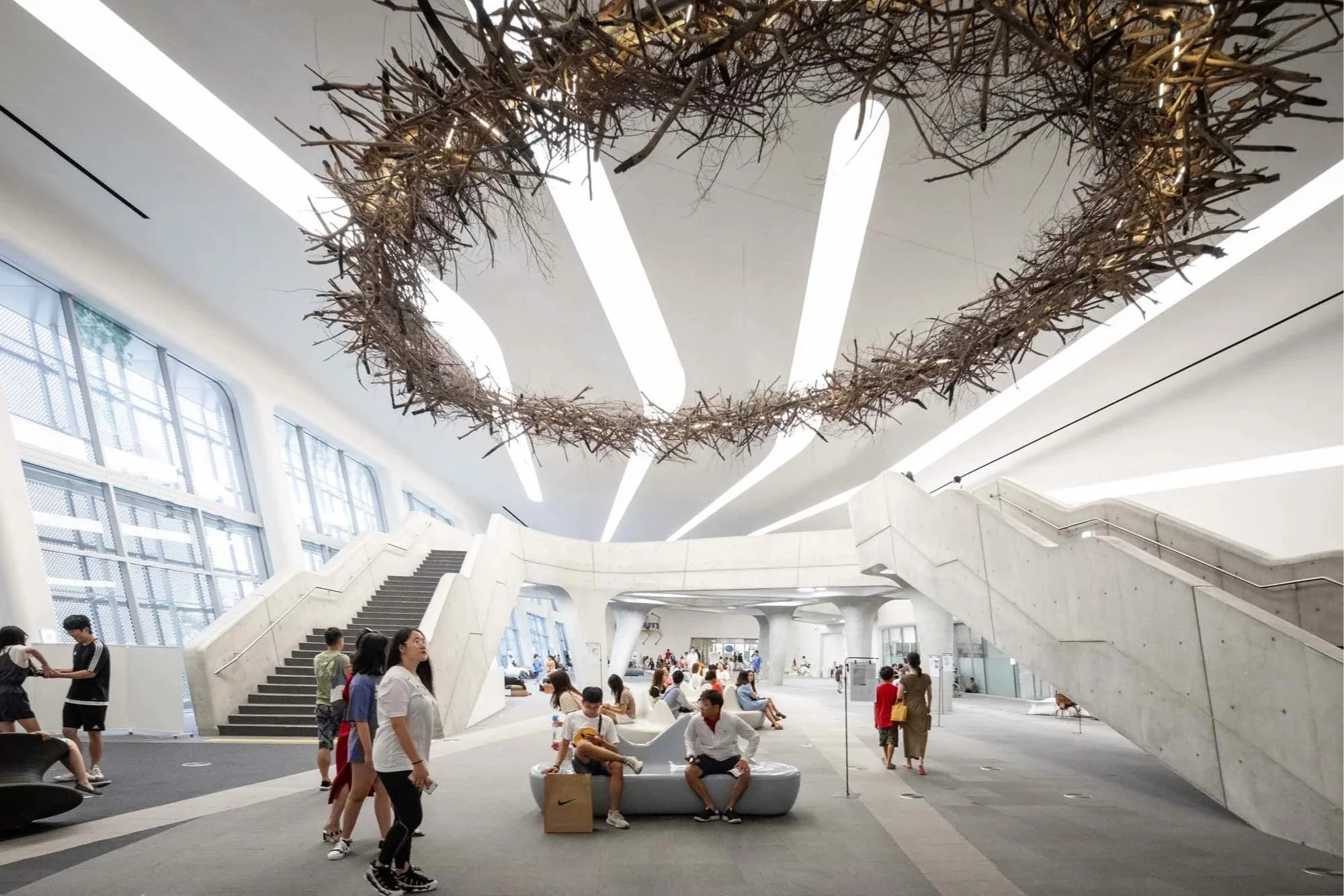 Zaha Hadid - Dongdaemun Design Plaza - Modern Architecture White Spacious People Staircase Seating Windows Bright Artistic Installation Ceiling Lights Gathering Space Natural Light Minimalis