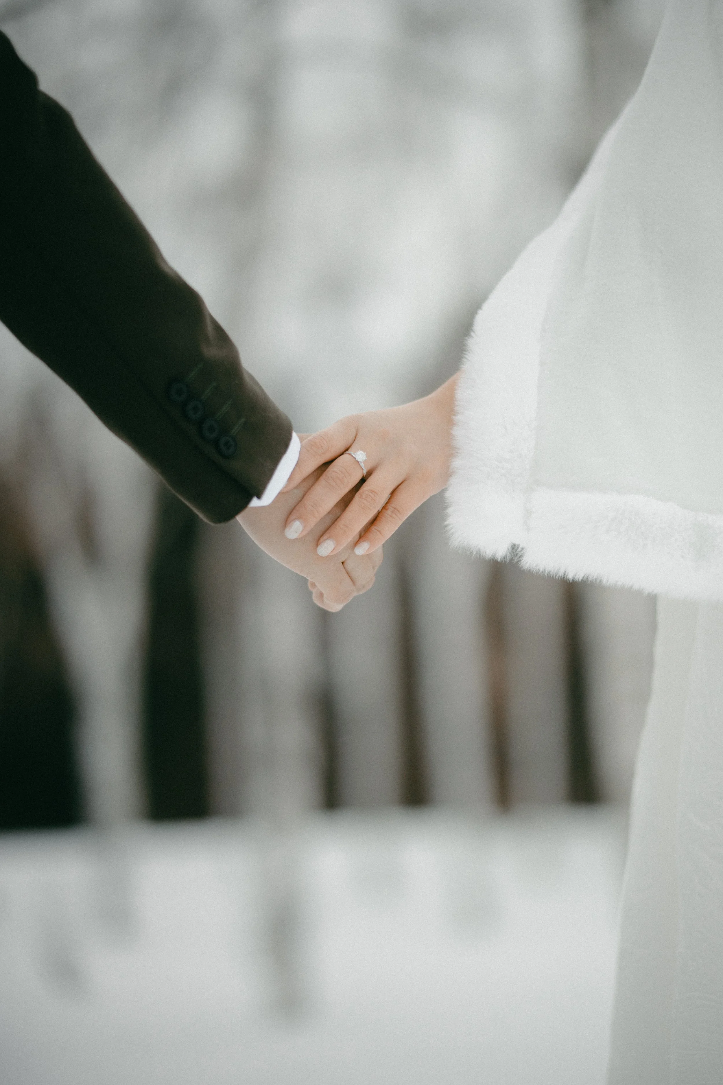 Close-up of a bride and groom holding hands during their wedding ceremony, showing the bride's wedding ring.