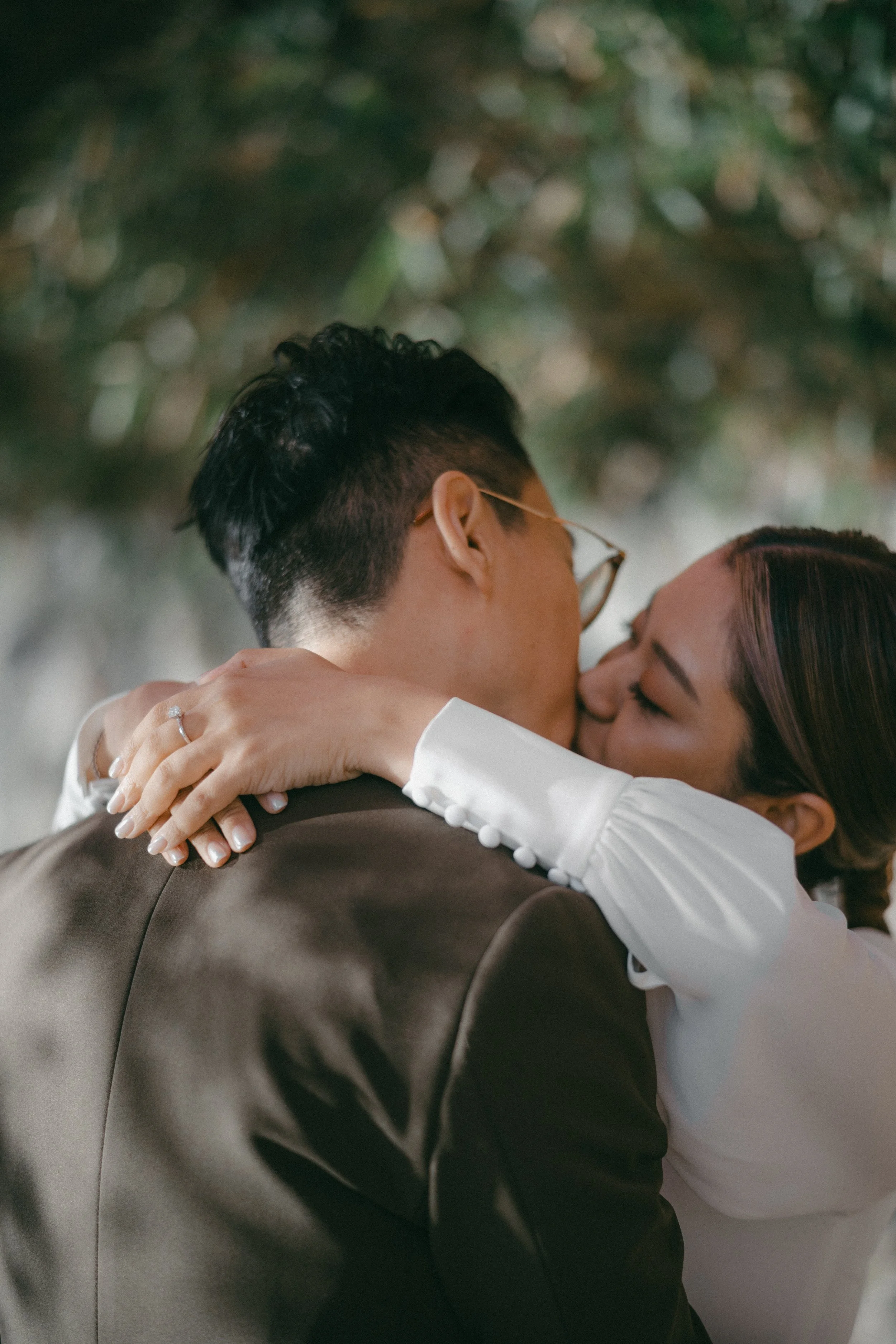 A couple sharing a kiss, with the woman embracing the man, during a wedding or special event.