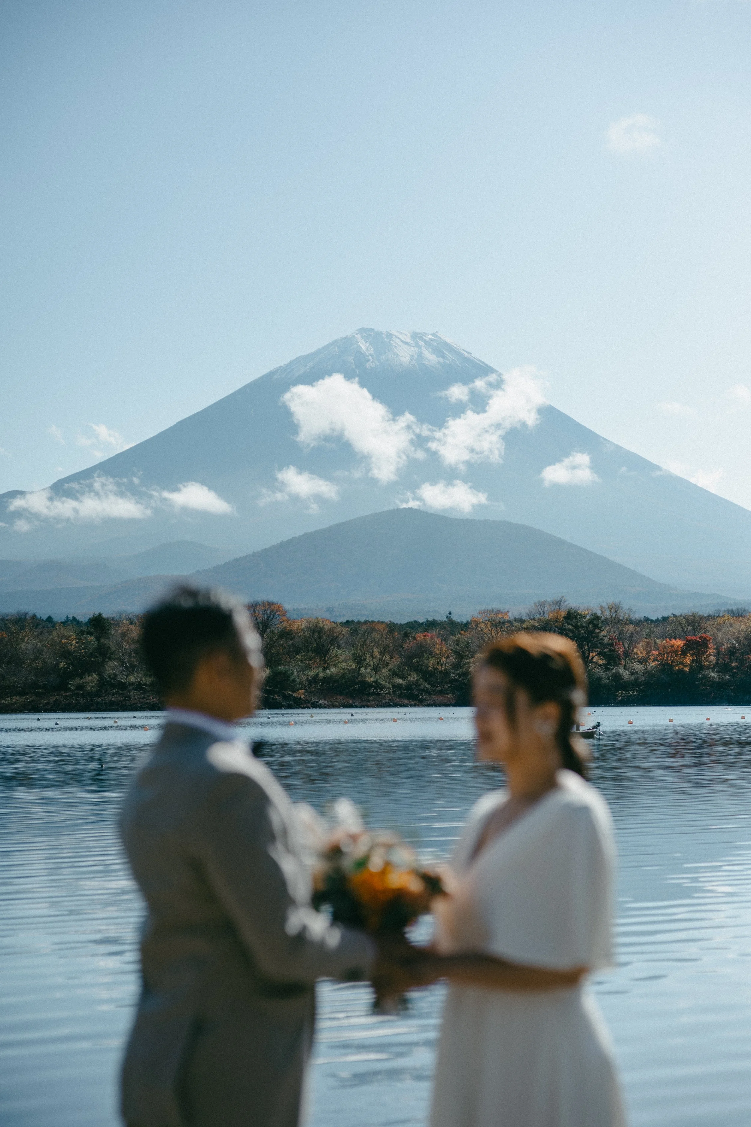 A couple getting married by a lake with Mount Fuji in the background.