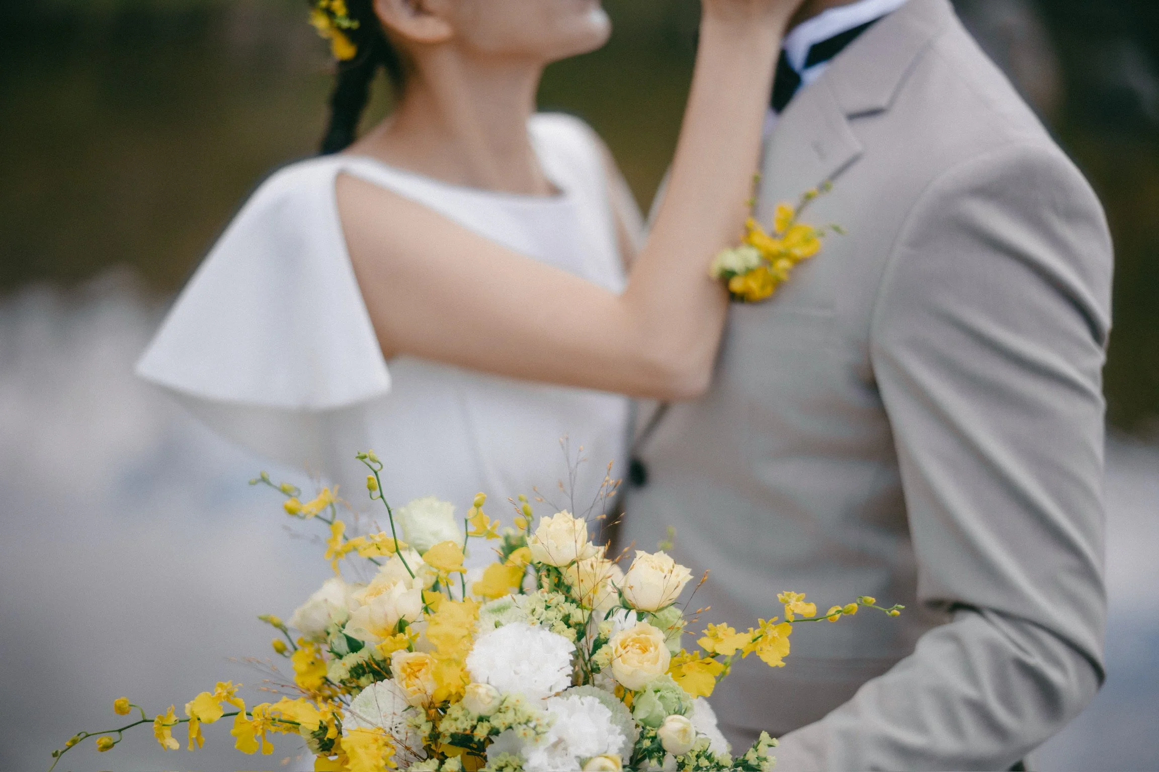 A bride and groom holding a yellow and white flower bouquet during their wedding.