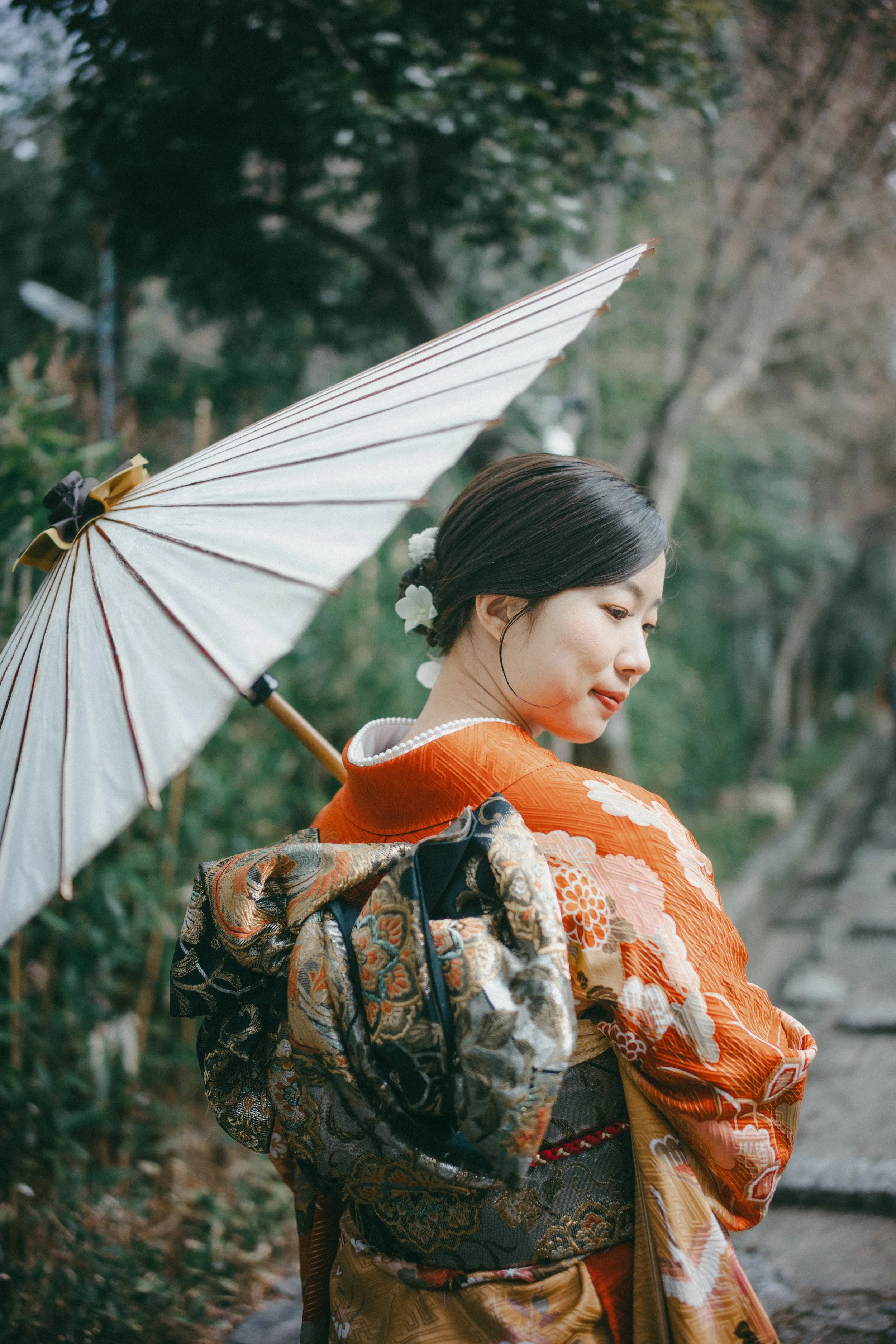 A woman in a traditional Japanese kimono holding a parasol outdoors.