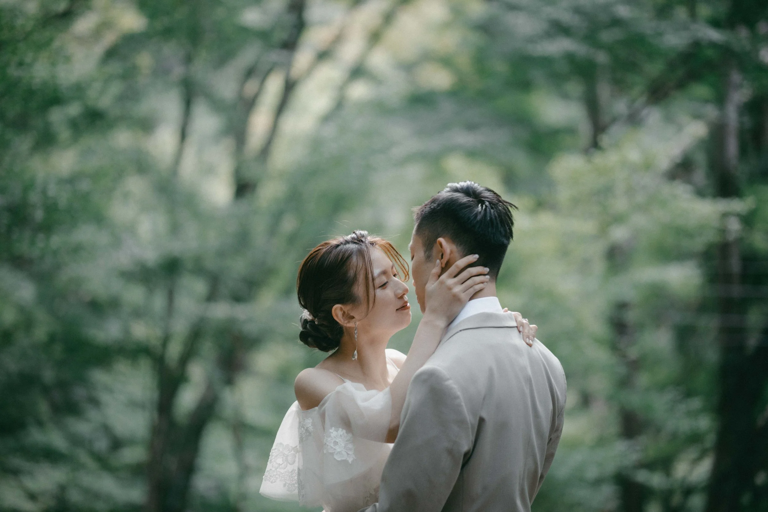 A couple in wedding attire sharing an intimate moment outdoors in a forest setting