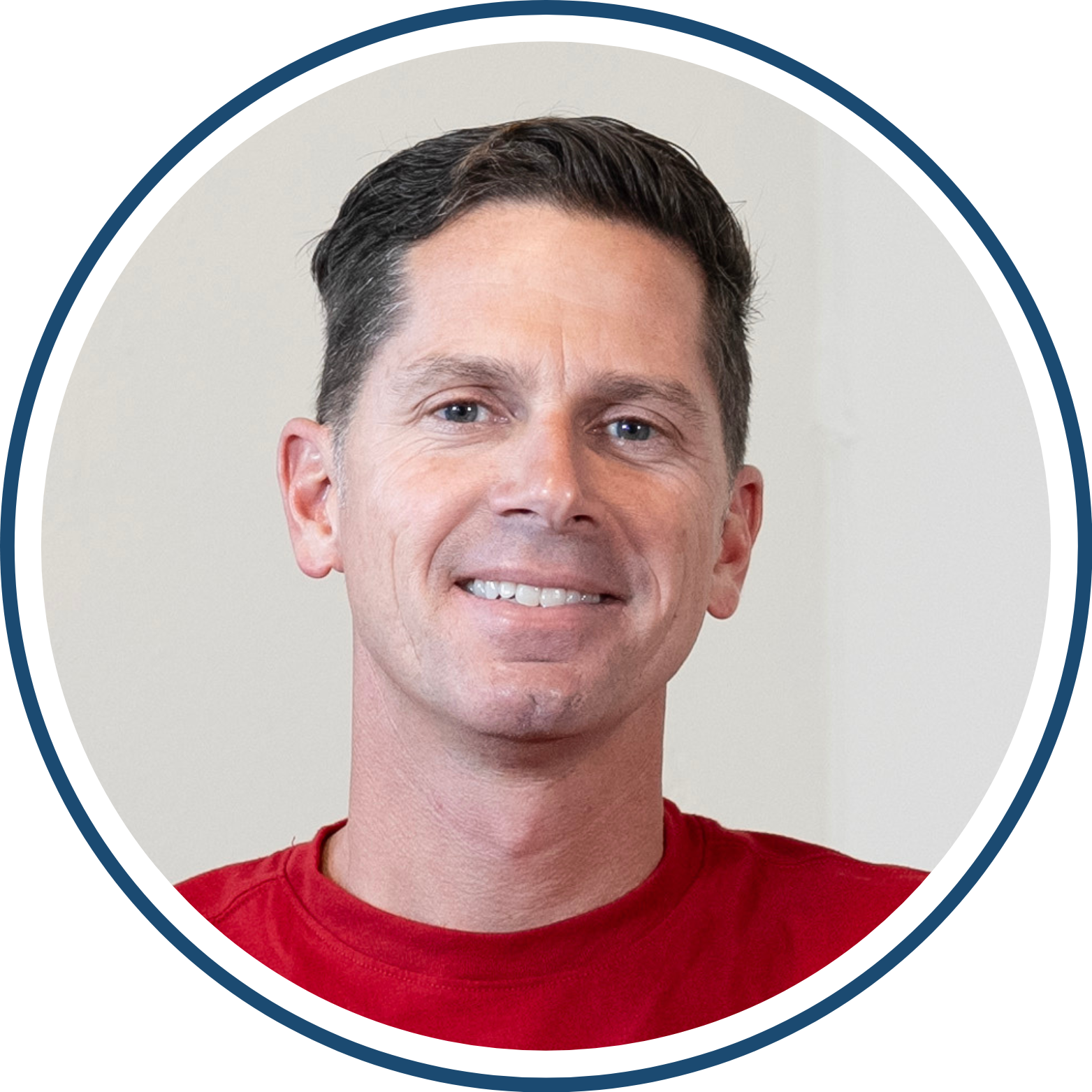 Portrait of a person smiling, wearing a red shirt, with short dark hair.