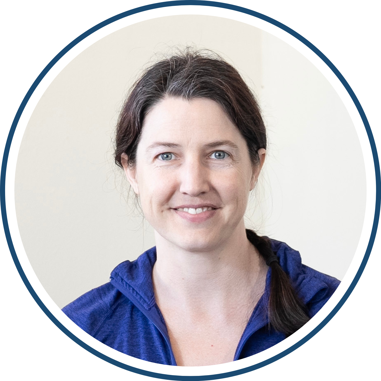 A person with dark hair wearing a blue hoodie, smiling at the camera.