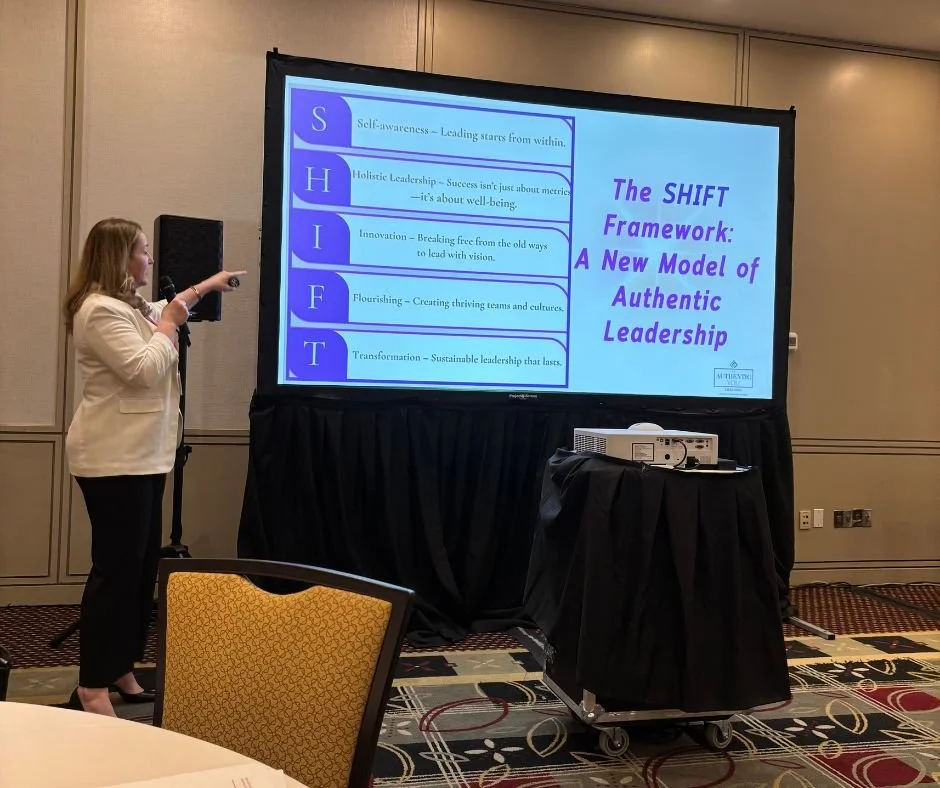 Kristina Holle - speaker  giving a presentation on a screen titled 'The SHIFT Framework: A New Model of Authentic Leadership'. The slide lists five components: Self-awareness, Holistic Leadership, Innovation, Flourishing, and Transformation.