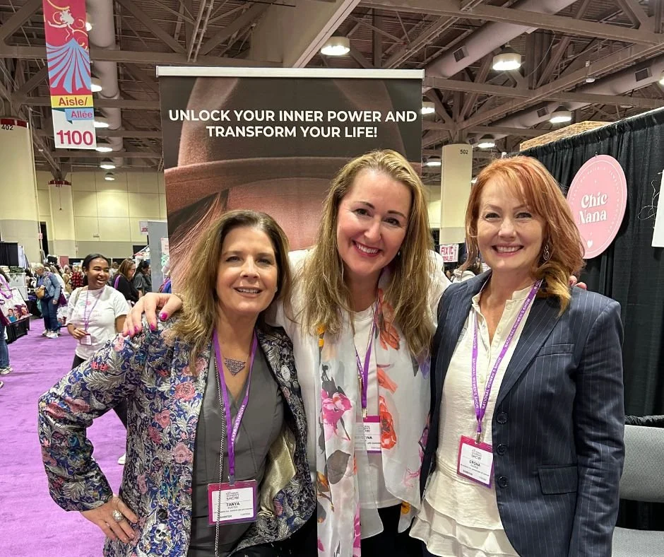 Kristina Holle smiling and posing with two women at a professional conference, with booths and attendees in the background