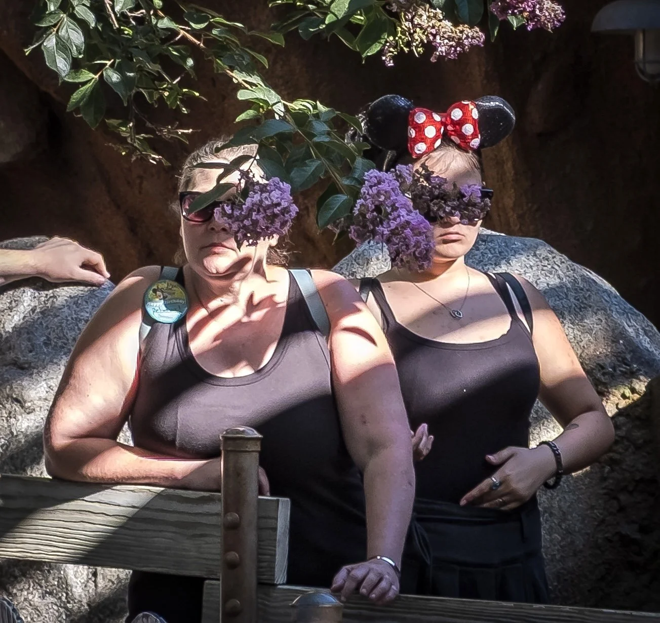 Two women with purple flowers in front of their faces.jpg