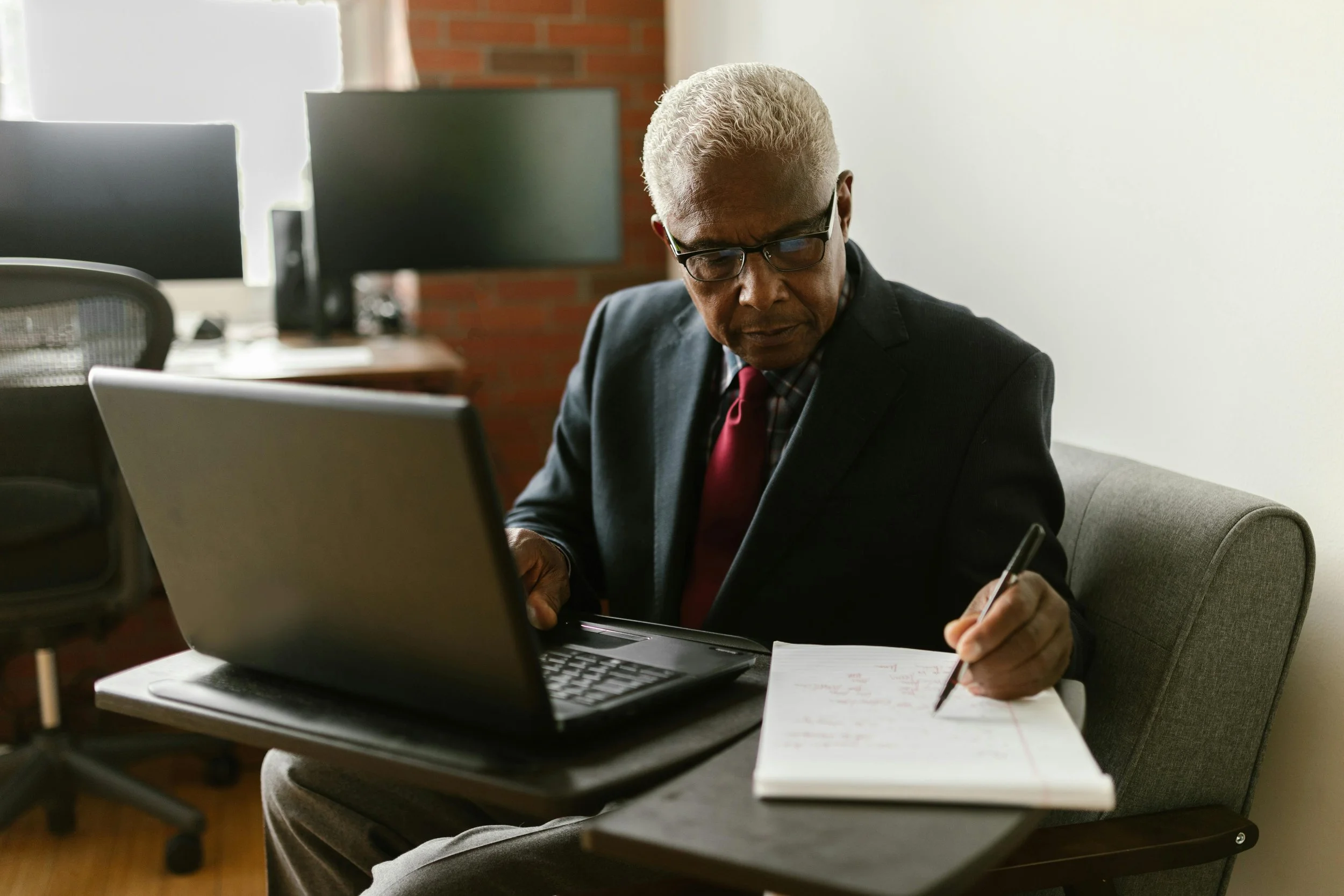A Man in Black Suit Writing on Paper
