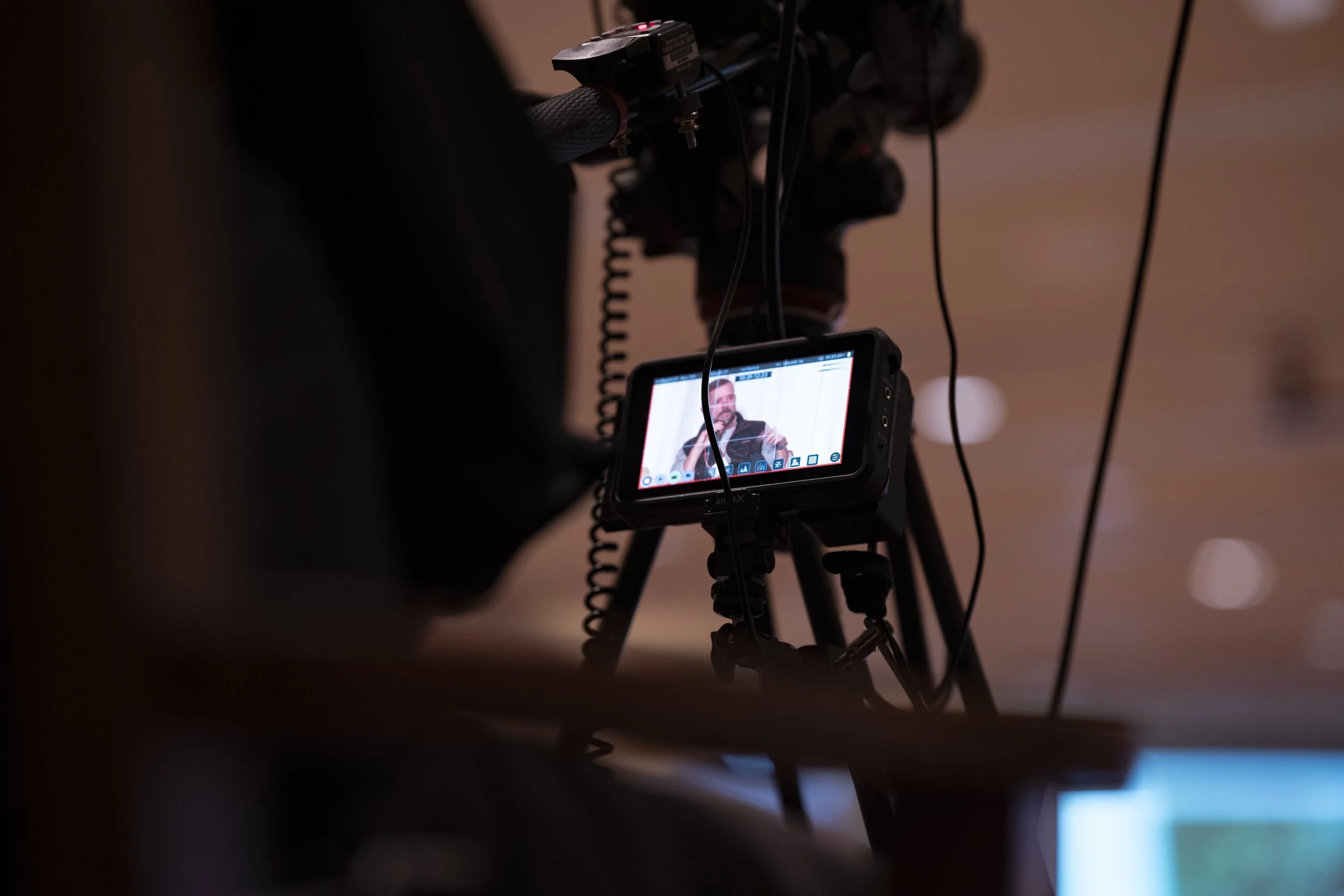 Camera on tripod recording a person speaking during an event.