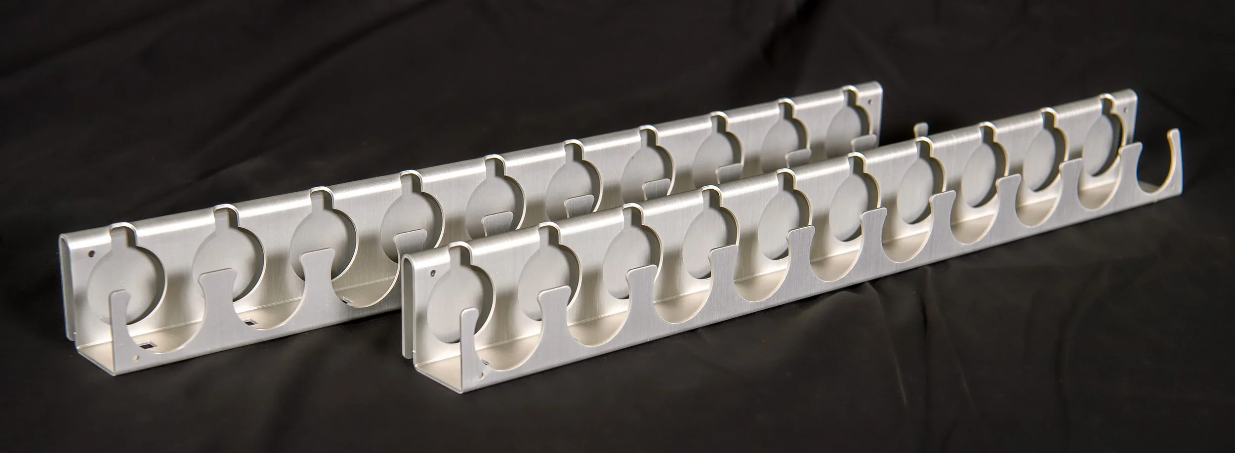 A metallic rack with multiple circular openings, placed on a black surface.