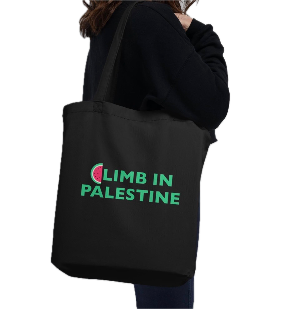 A person wearing a black hoodie carrying a black tote bag with the text 'Climb in Palestine' and a watermelon slice graphic.