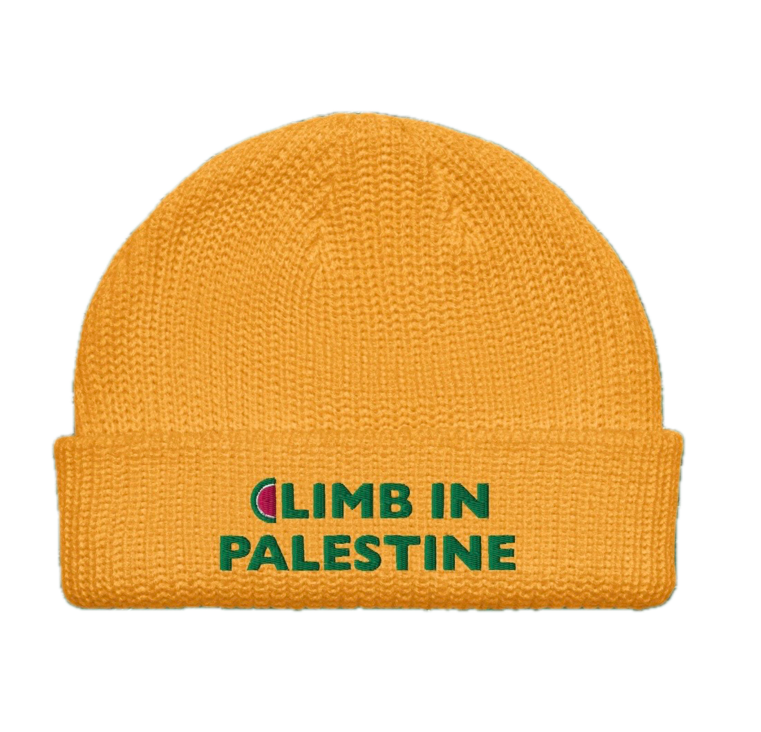 Yellow knit beanie hat with a folded brim that has green text saying "CLIMB IN PALESTINE."