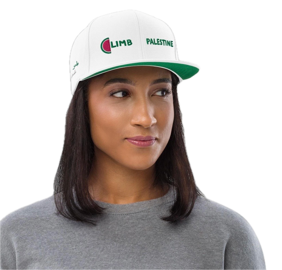 Woman wearing a white cap with green and red embroidery that reads 'Limb Palestine' and a gray shirt.