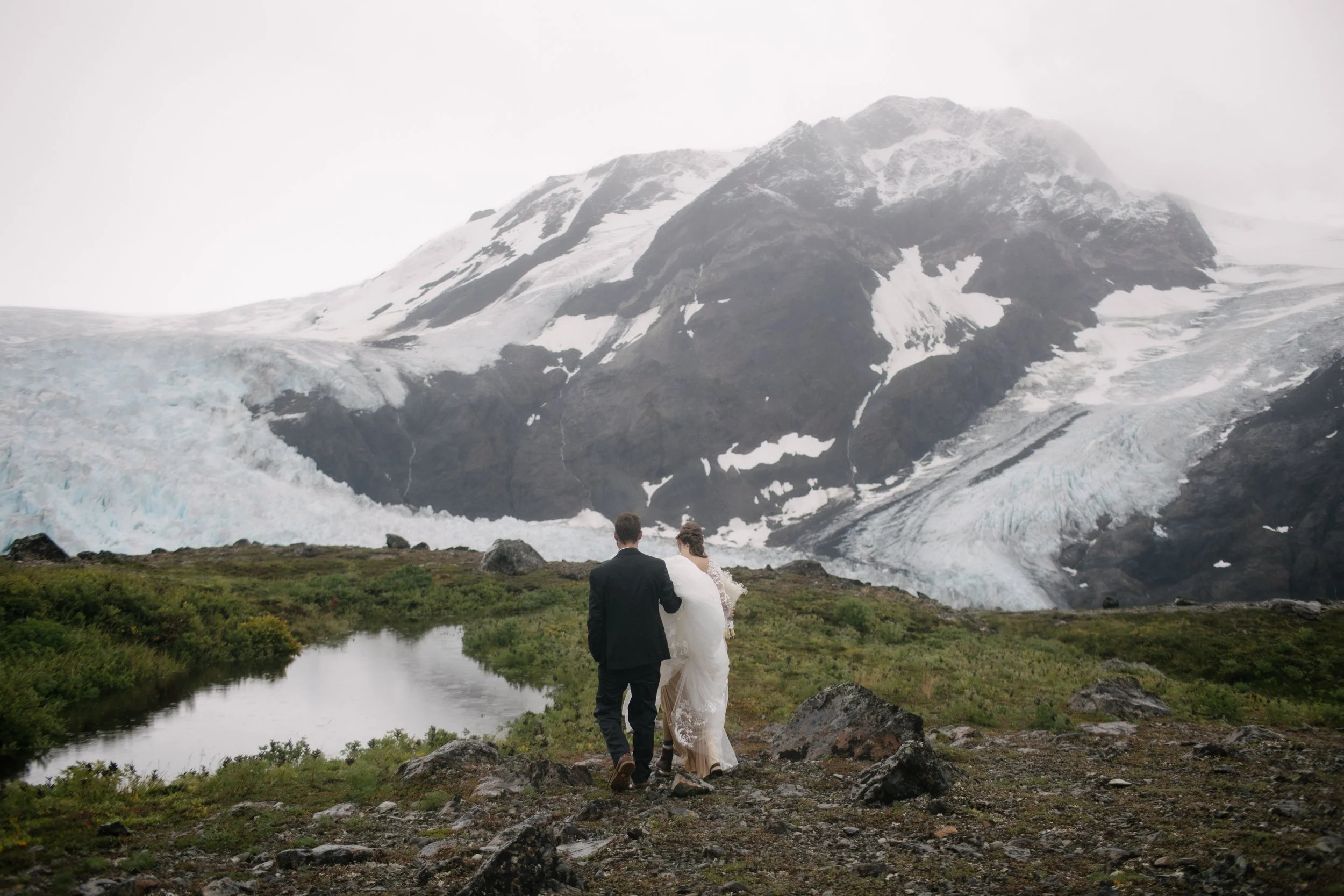couple eloping walking towards glacier 