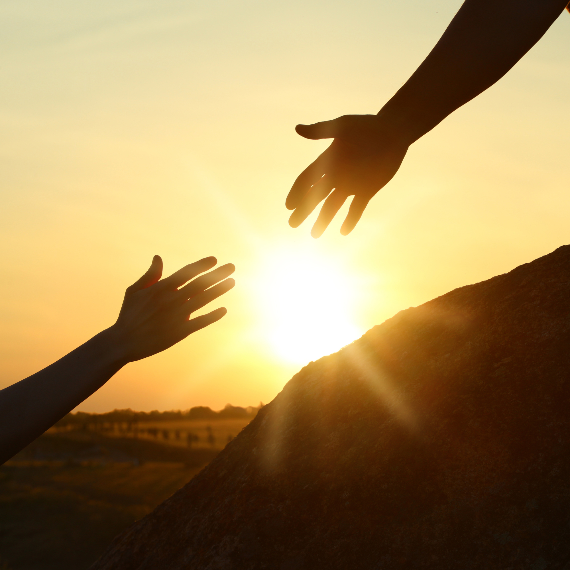 Two hands reaching toward each other in front of a warm sunset, symbolizing support and partnership in menopause and sexual health care at Glow Health by Andrea Martin