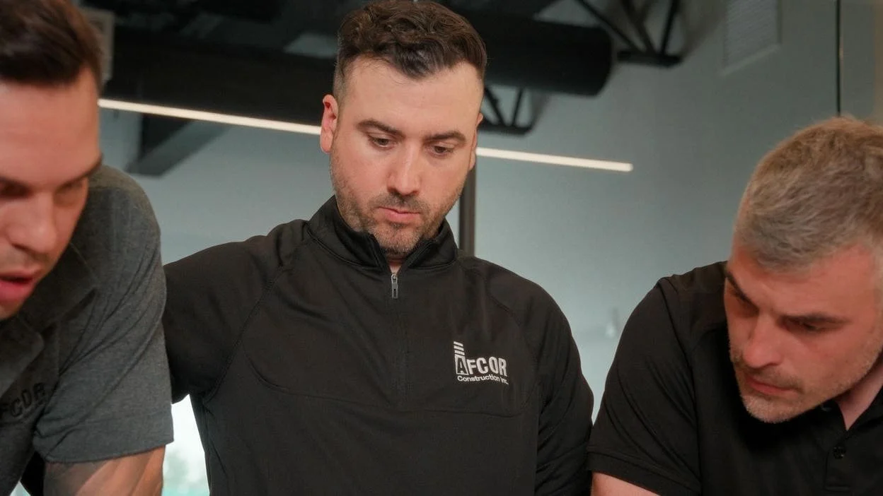 Three employees looking down at plan on table