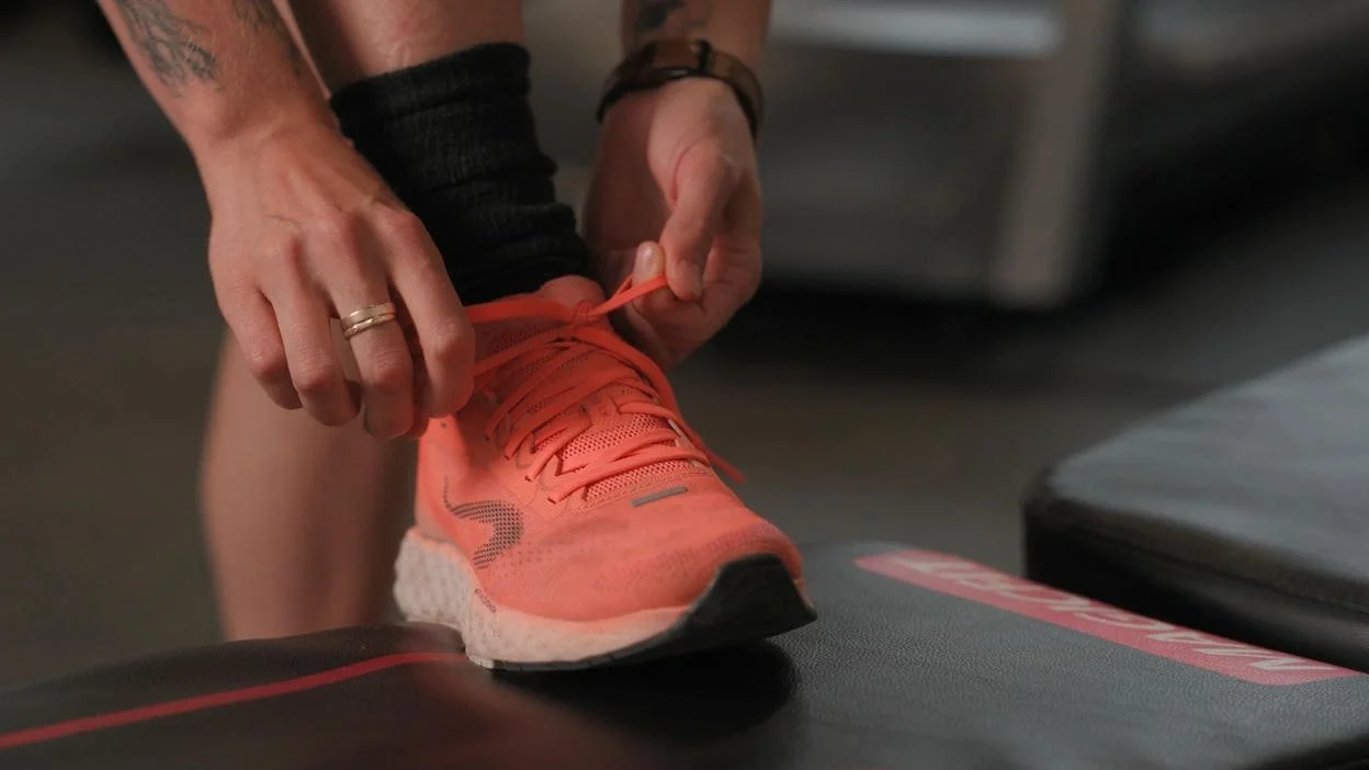 Closeup of orange running shoe being tied up