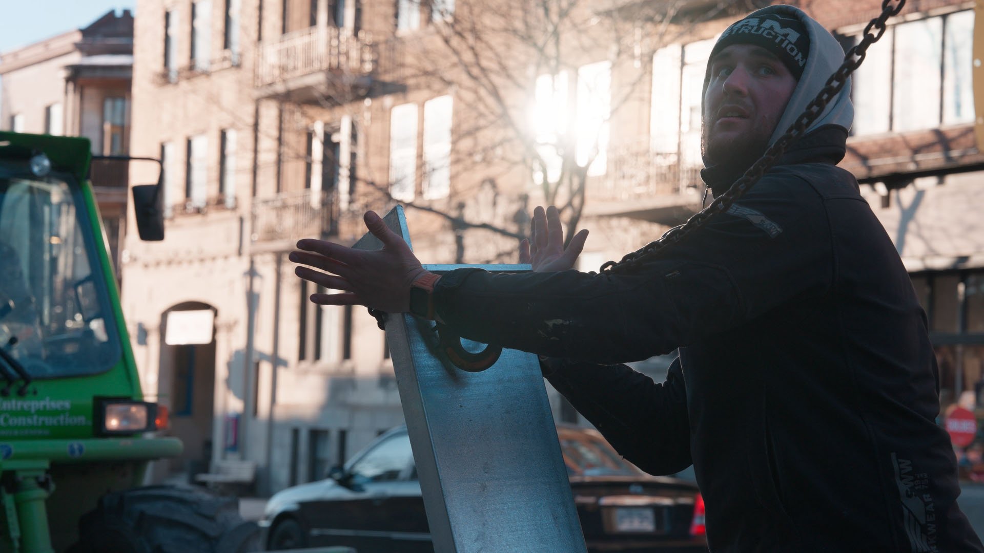 worker holding a steel beam hanging off a crane
