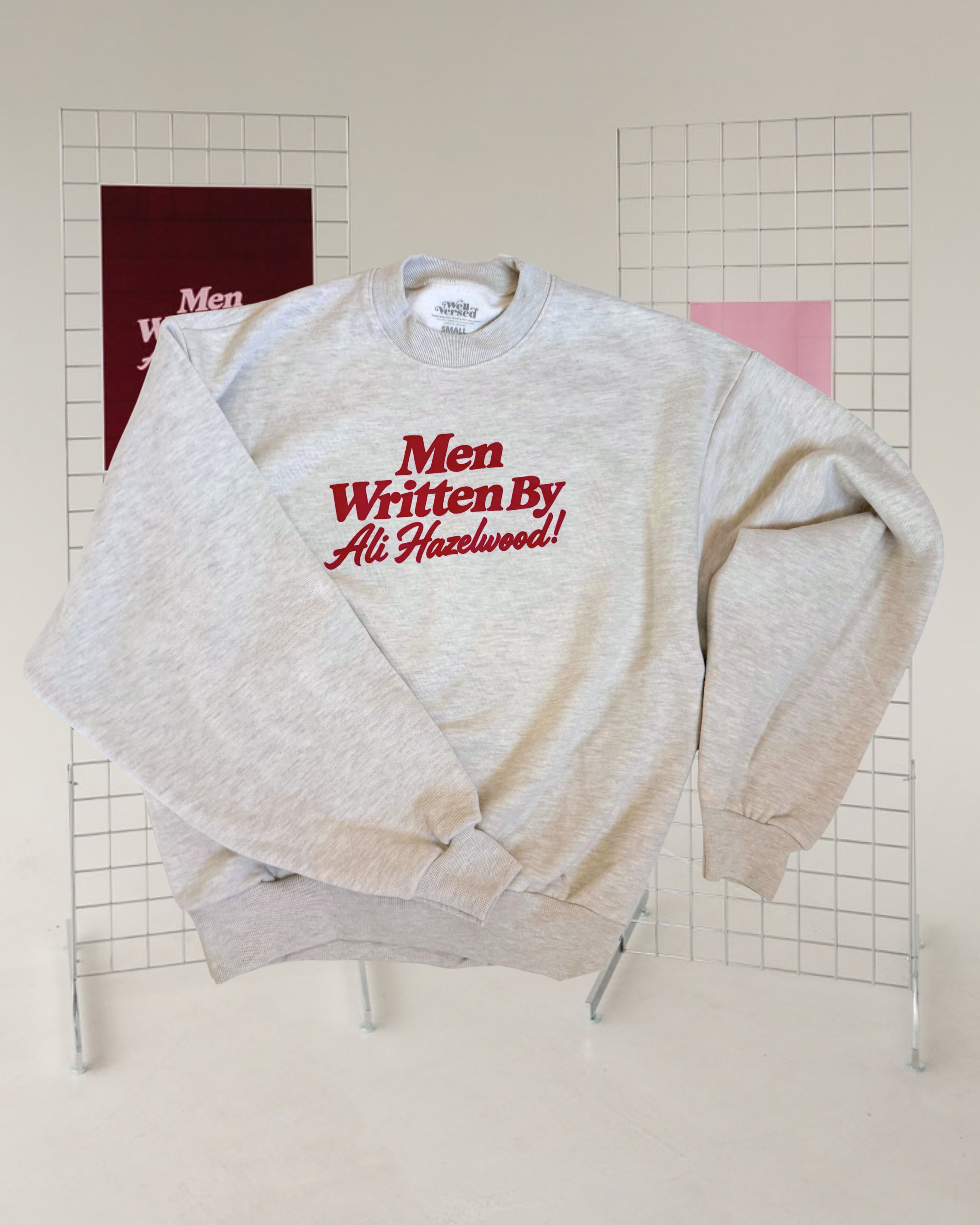 Grey marl crewneck sweatshirt with “Men Written by Ali Hazelwood” printed across the front in red.