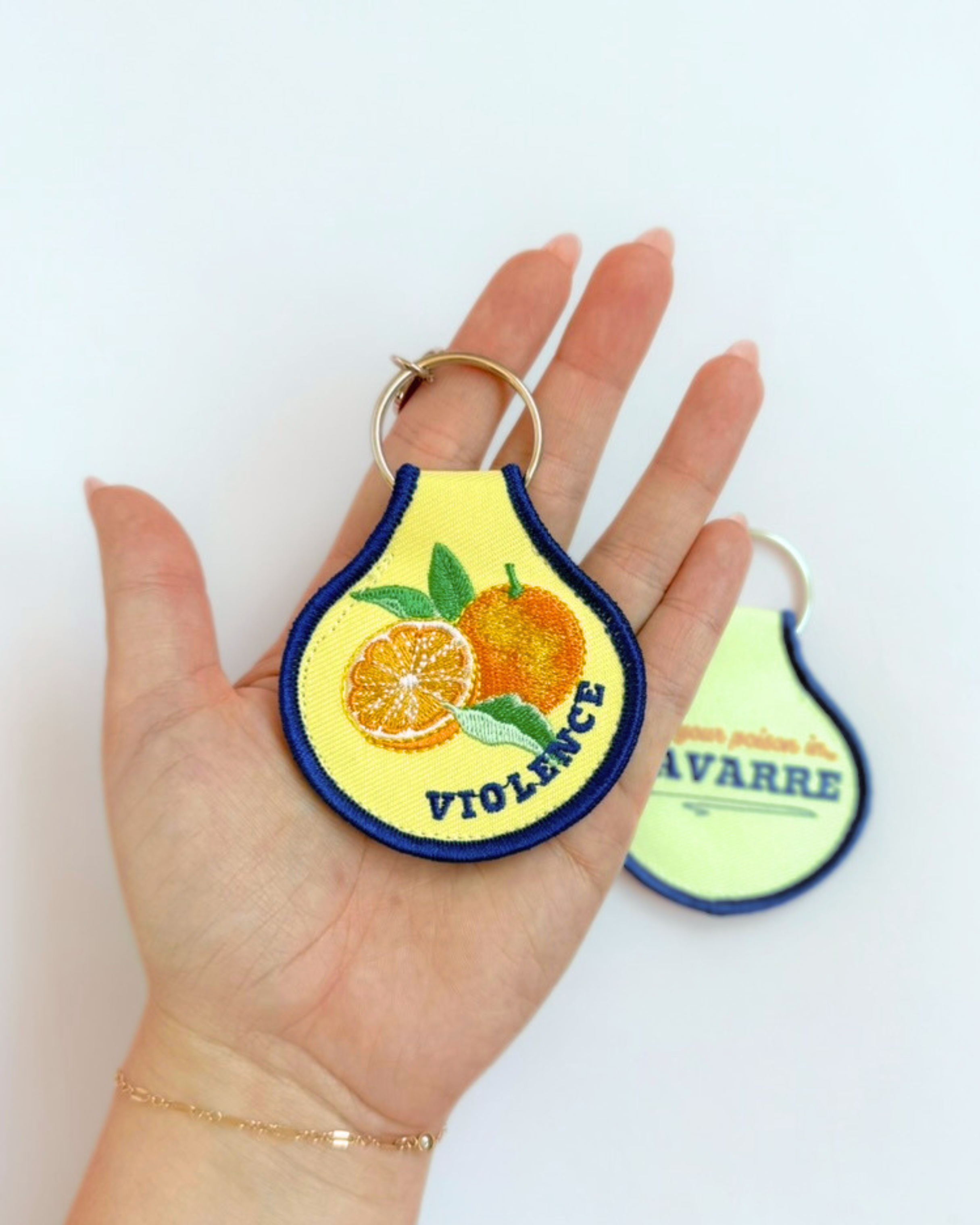 A cheeky embroidered keychain for romance and fantasy readers featuring a bright citrus design and “Violence” detail. A fun bookish accessory for keys, totes, and reading bags.