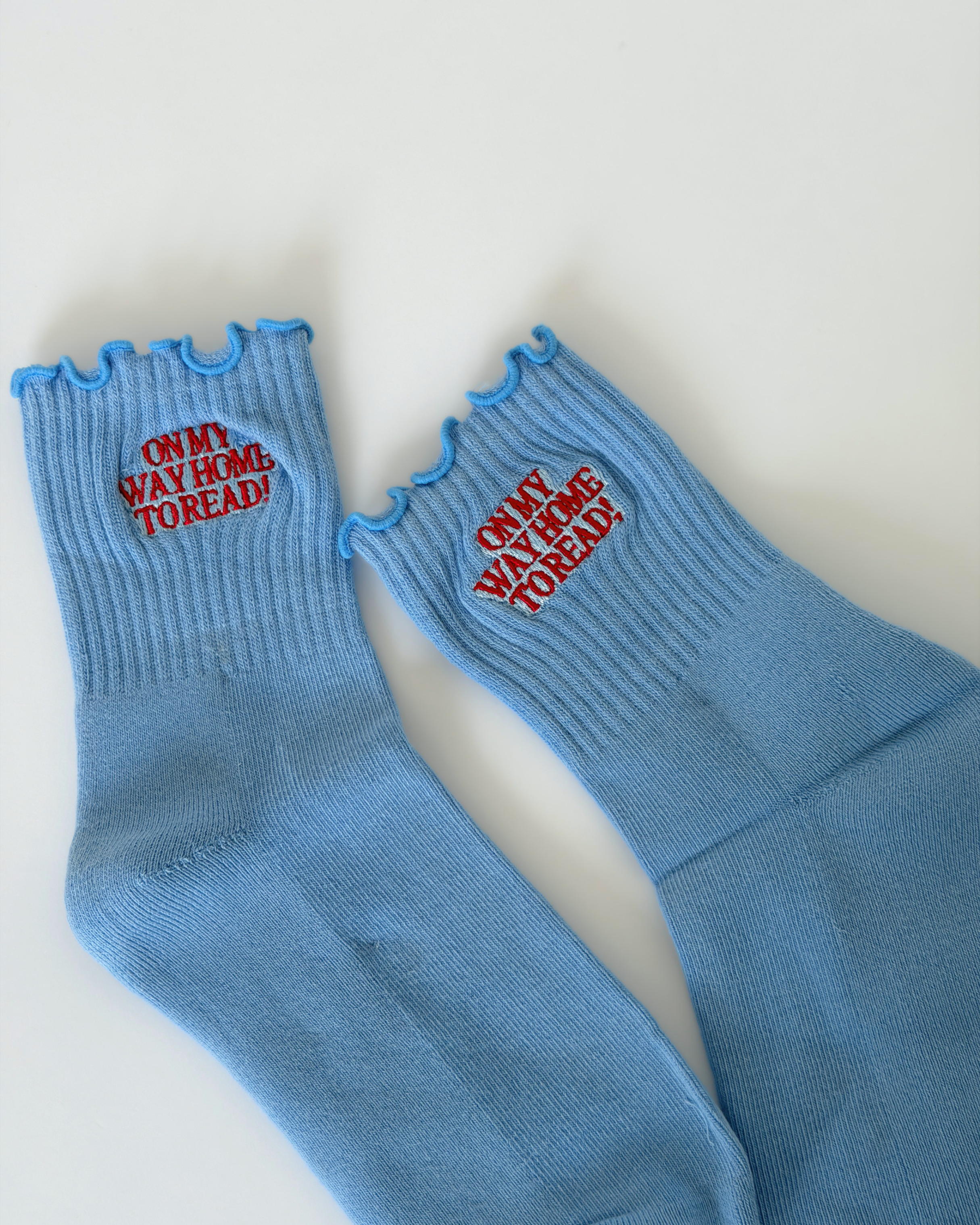 Blue sock with red writing that reads - OMW Home to Read