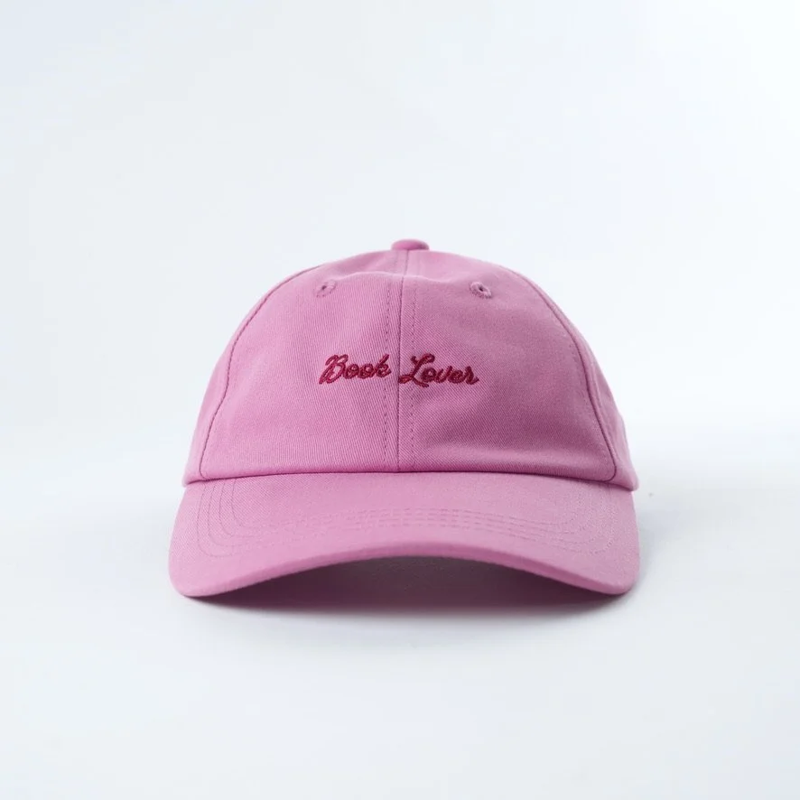 Pink embroidered hat that reads book lover in red cursive