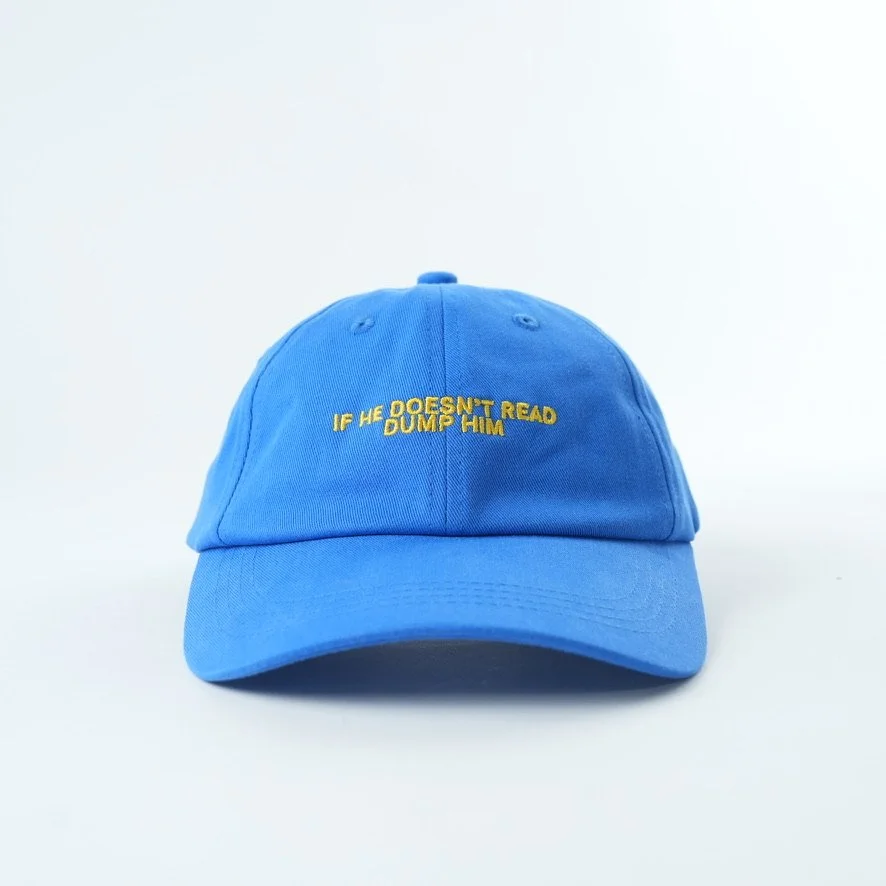 Bright blue cotton dad hat featuring yellow embroidered text that reads “IF HE DOESN'T READ DUMP HIM.
