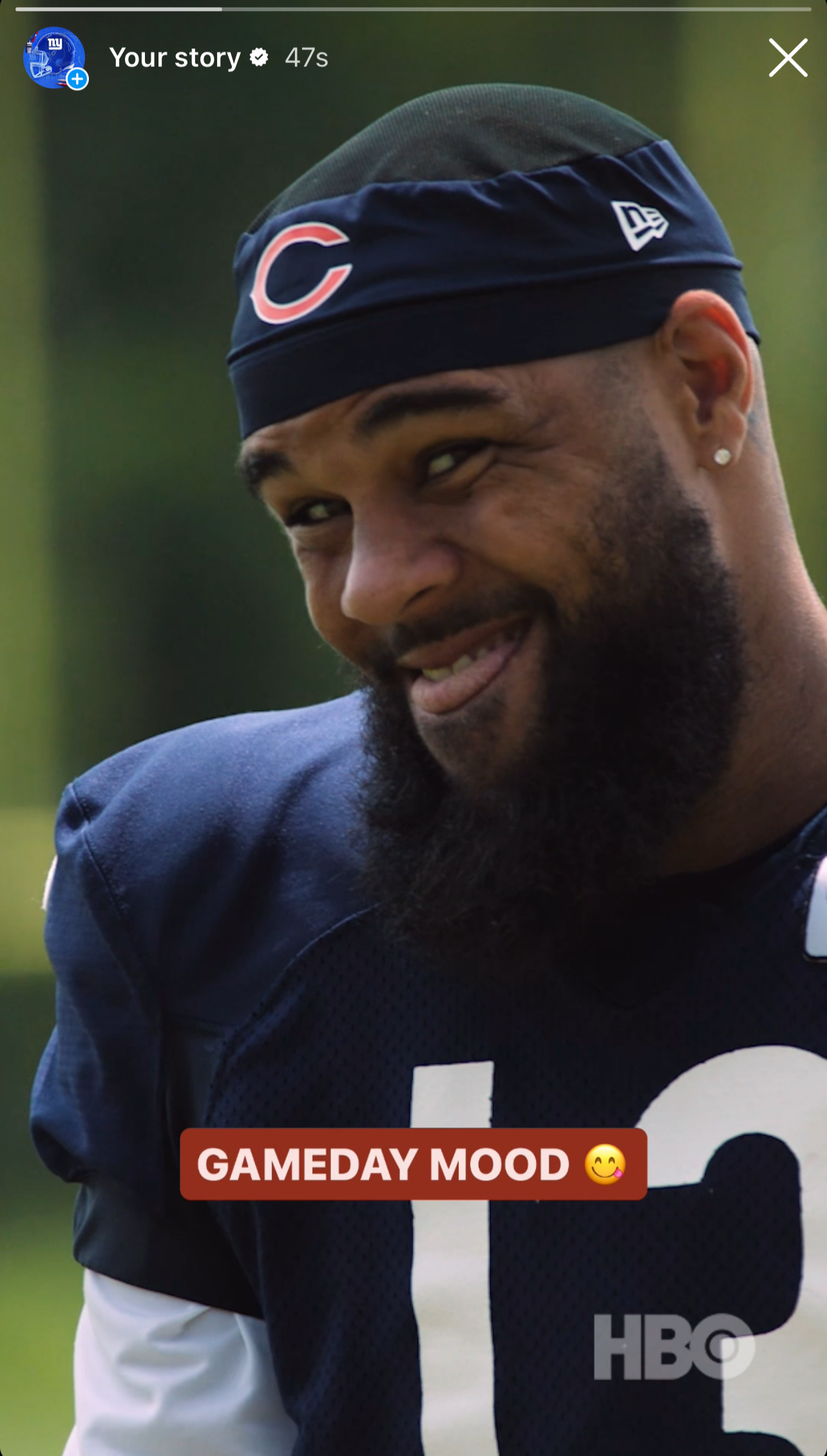 Close-up of a football player wearing a navy blue jersey with the number 18, a navy headband with a red and white 'C' logo, and a diamond earring. The background is blurred green. Text overlay says 'GAMEDAY MOOD' with a smiley face emoji. HBO logo at bottom right.