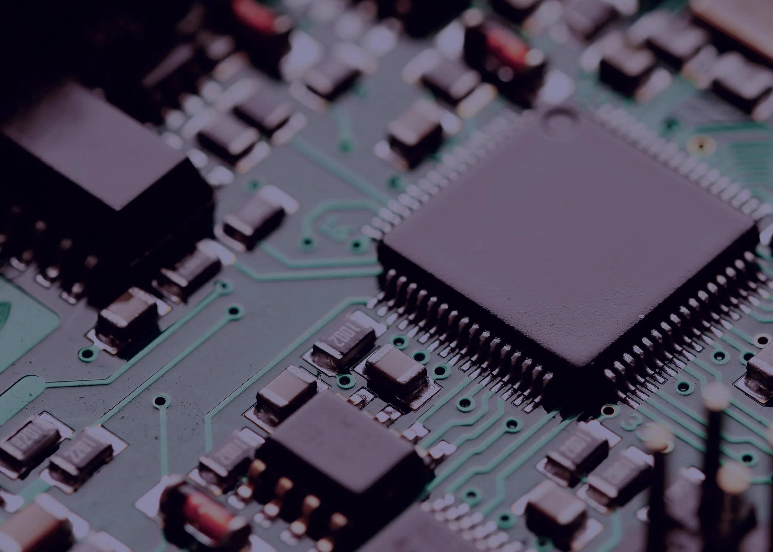 Close-up of a PCB with integrated circuits and surface-mount components manufactured to high-quality electronics standards.