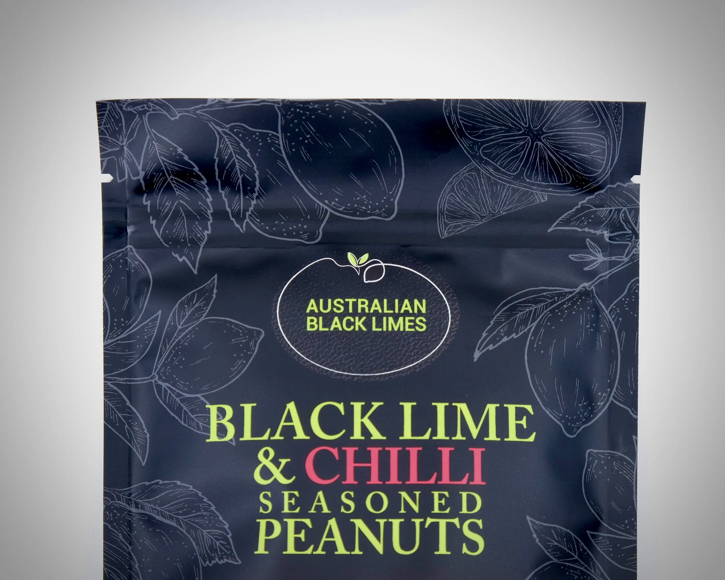 Packaging of Australian black limes and chili seasoned peanuts, navy blue background with white line drawings of citrus fruits, leaves, and herbs, with text highlighting the product as black lime and chili seasoned peanuts.