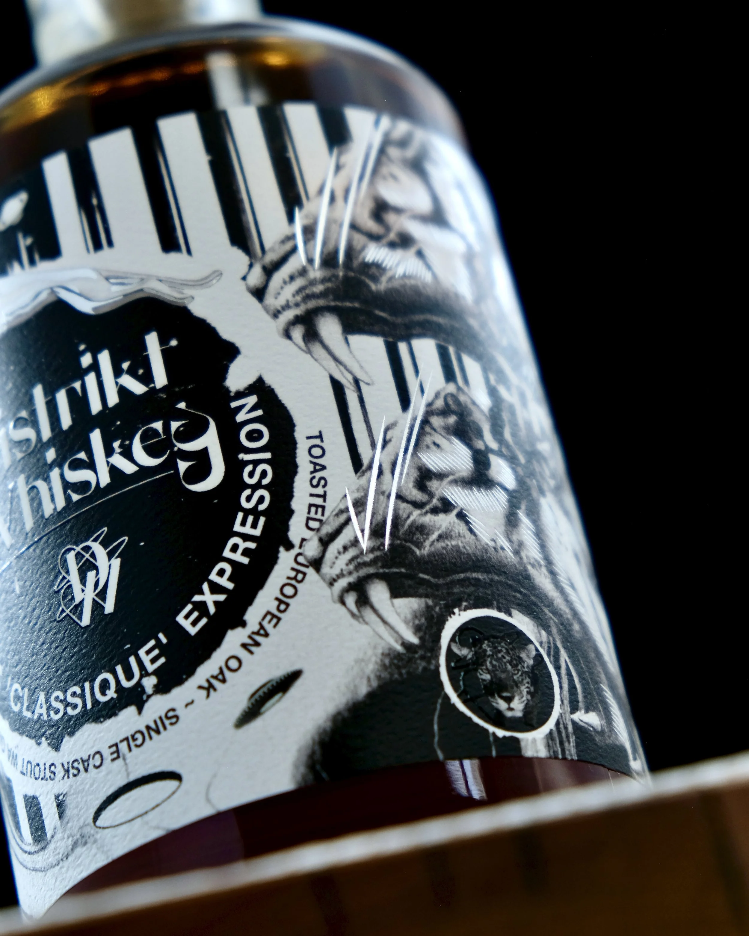 Close-up of a whiskey bottle with an embellished label set against a black background.