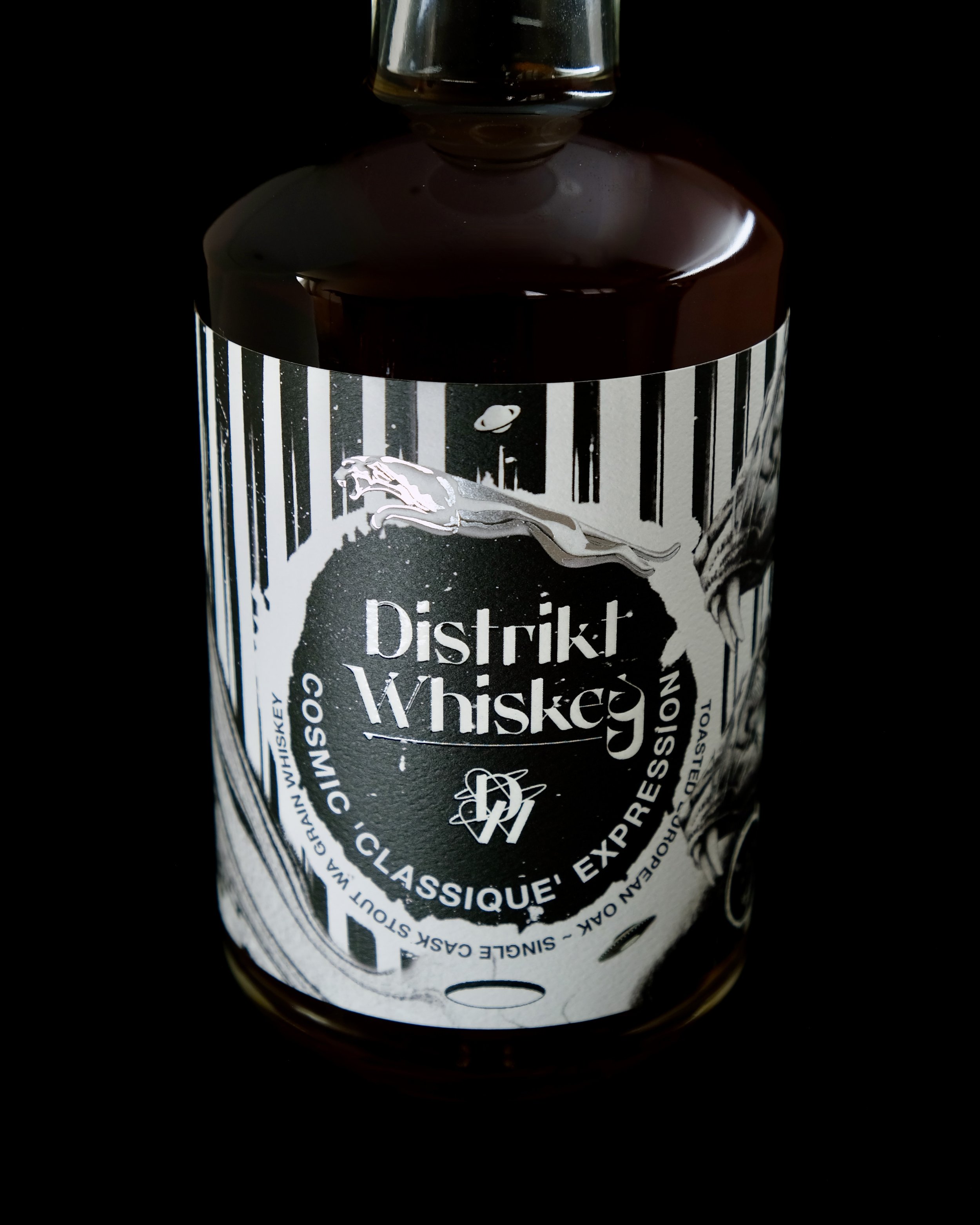 A bottle labeled 'Distrikt Whiskey' with a black and white design featuring a leaping panther and vertical stripes.