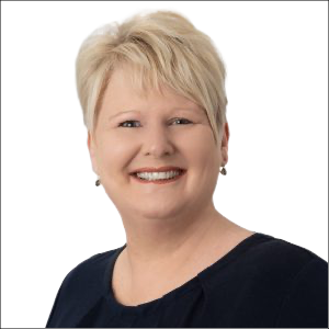 Portrait of a smiling middle-aged woman with short blonde hair, wearing a dark top.