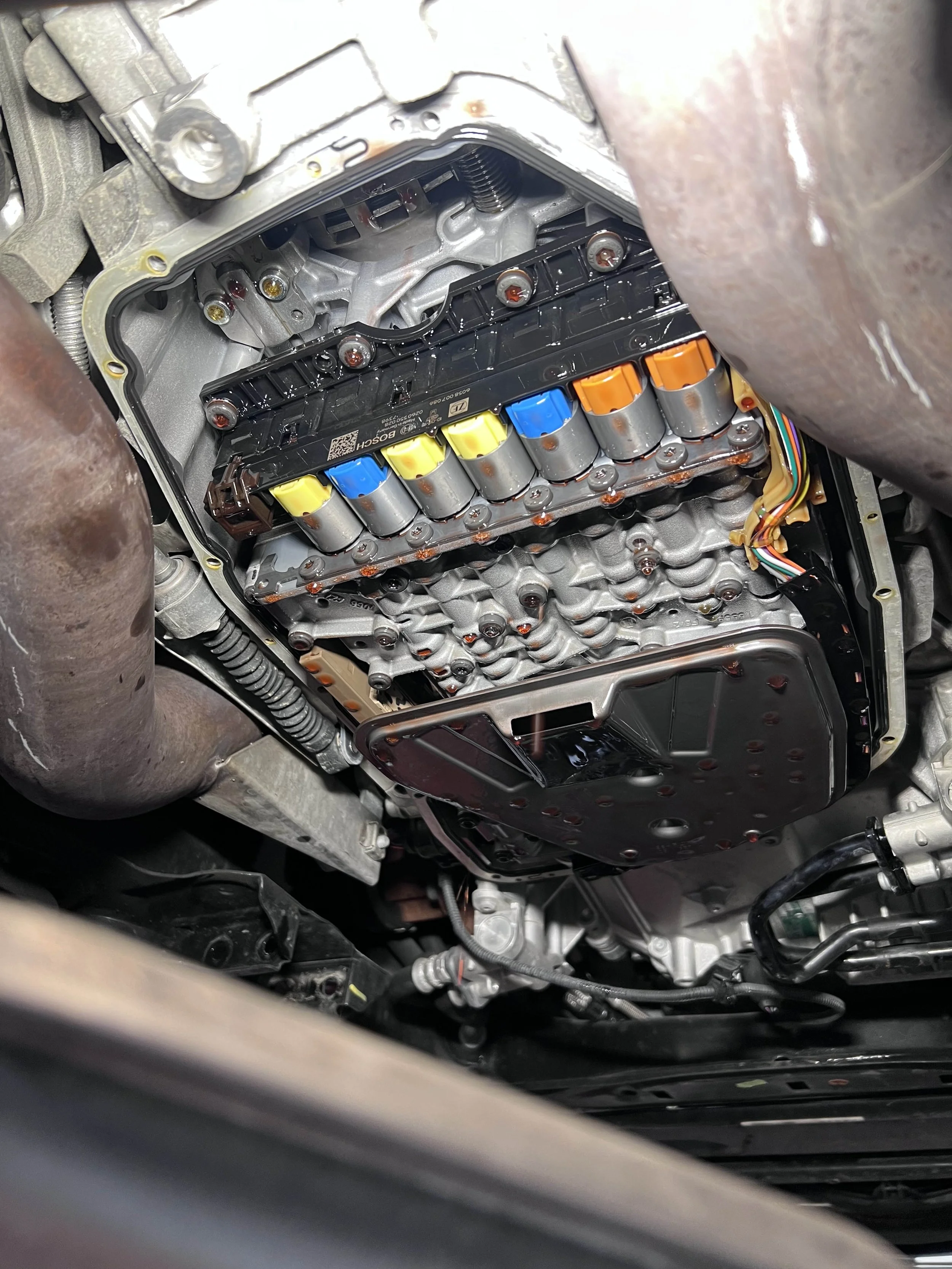 Immagine di un meccanismo di trasmissione automatica di un'auto con componenti visibili come il convertitore di coppia e il modulo di controllo elettronico.
