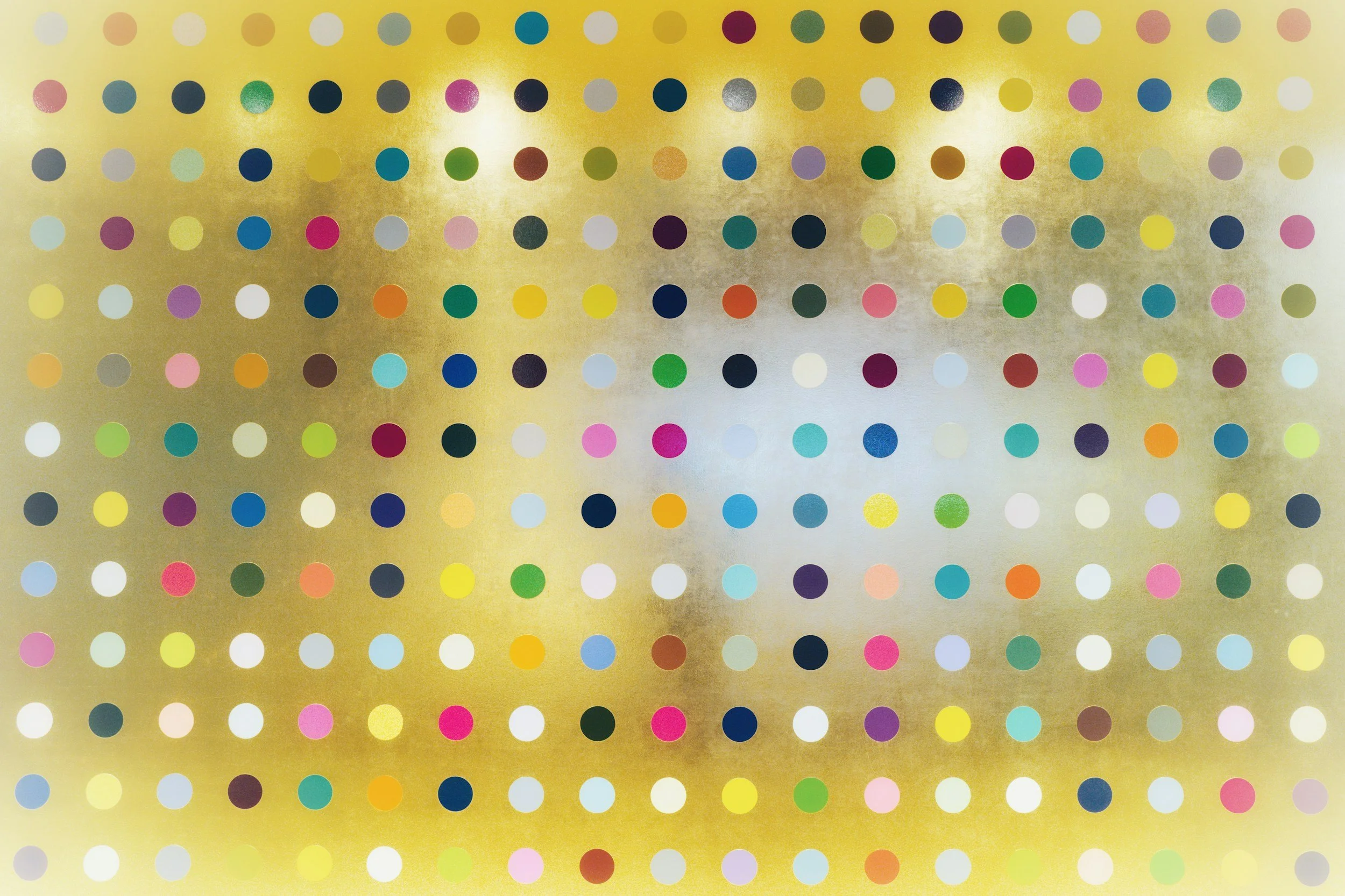 An abstract piece of artwork. There is a yellow background with equally-spaced small dots over the top, which are coloured blue, red, yellow, green, purple, black and other colours.