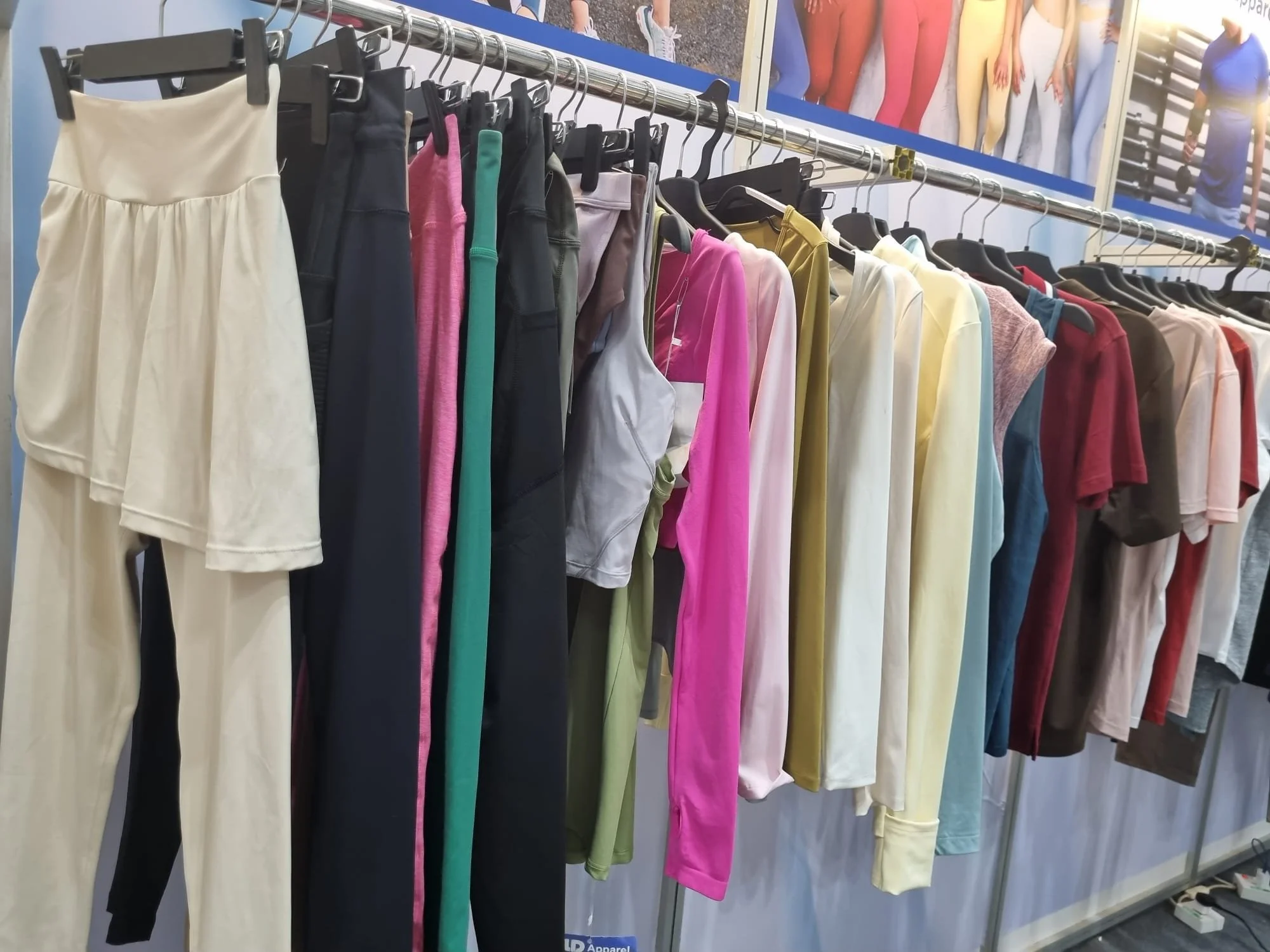 Custom apparel manufacturer booth at a textile trade show highlighting OEM and ODM clothing production services.