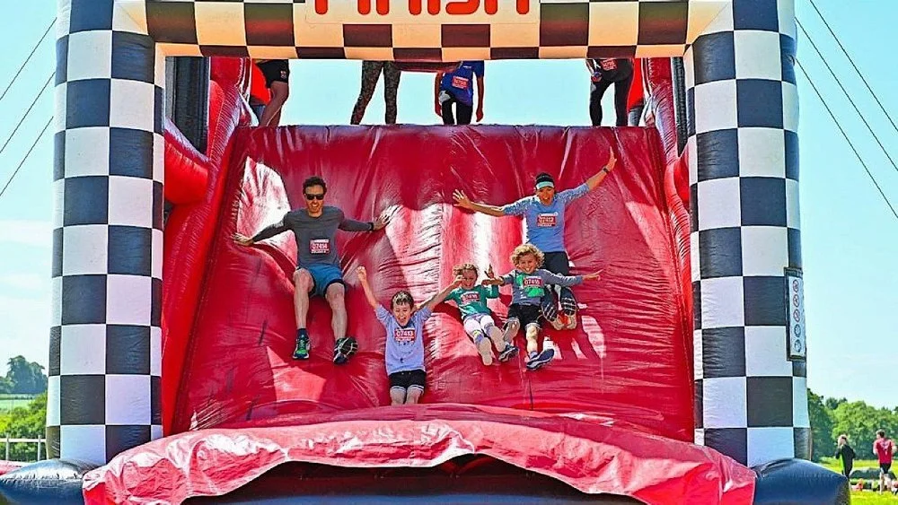 Participants sliding down a giant inflatable obstacle during an Inflatable 5k event