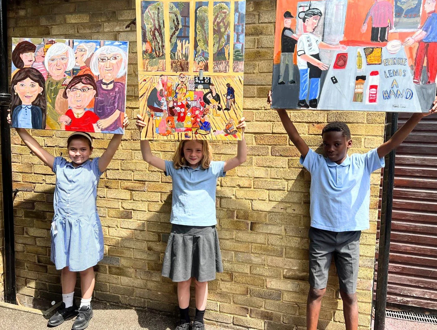 Children holding paintings inspired by Songs & Smiles, selected for the Royal Academy Summer Exhibition