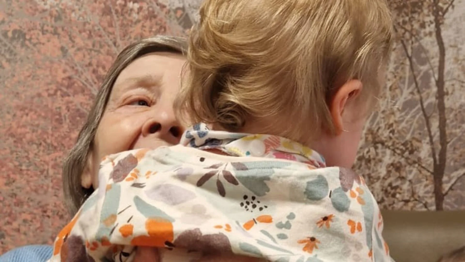 Close up image of a care home resident cuddling a young child