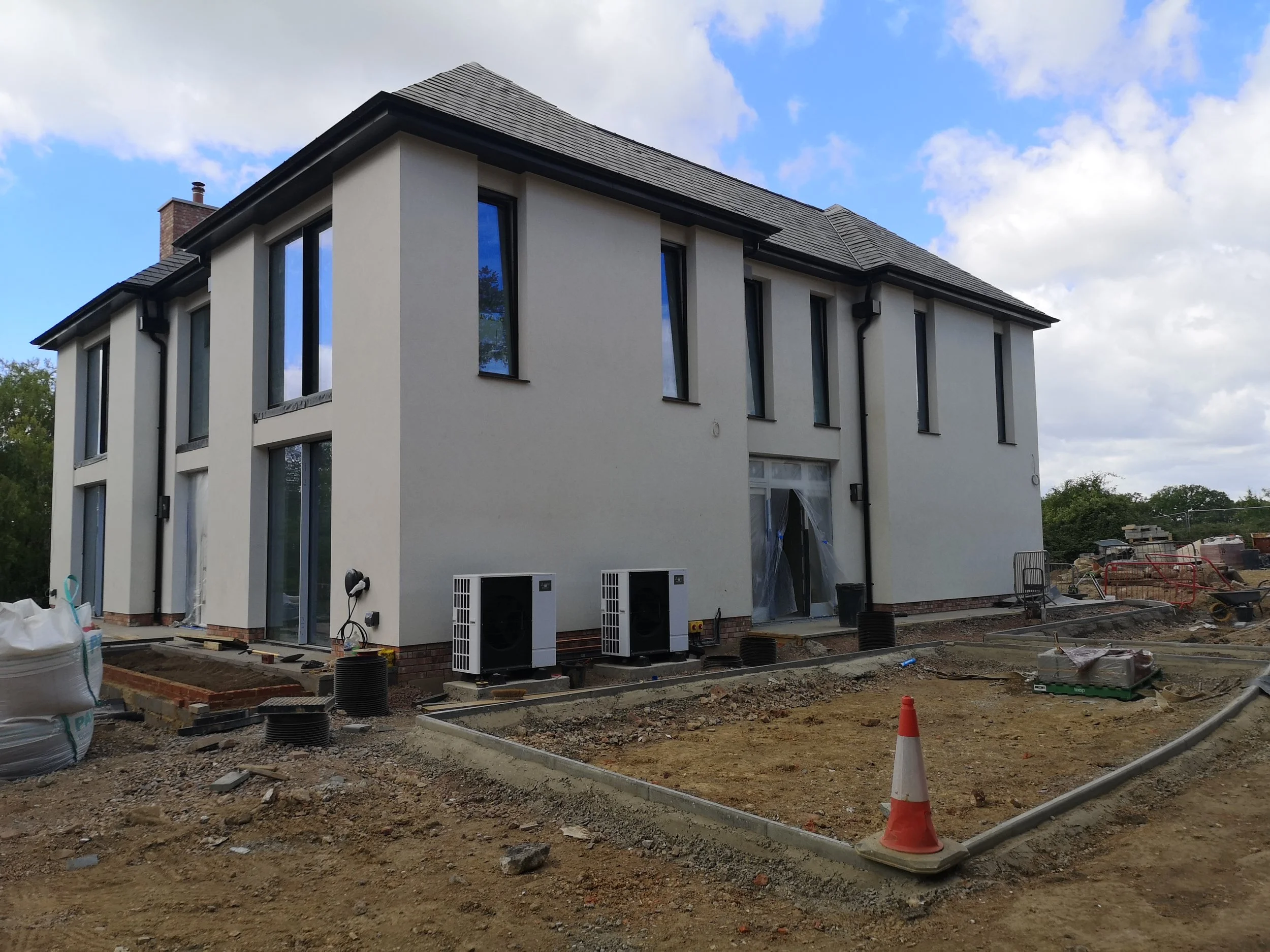 Pell Stevens Architects West Sussex countryside home site progress. Air source heat pump. Render. Slate roof. Contemporary home. New build.