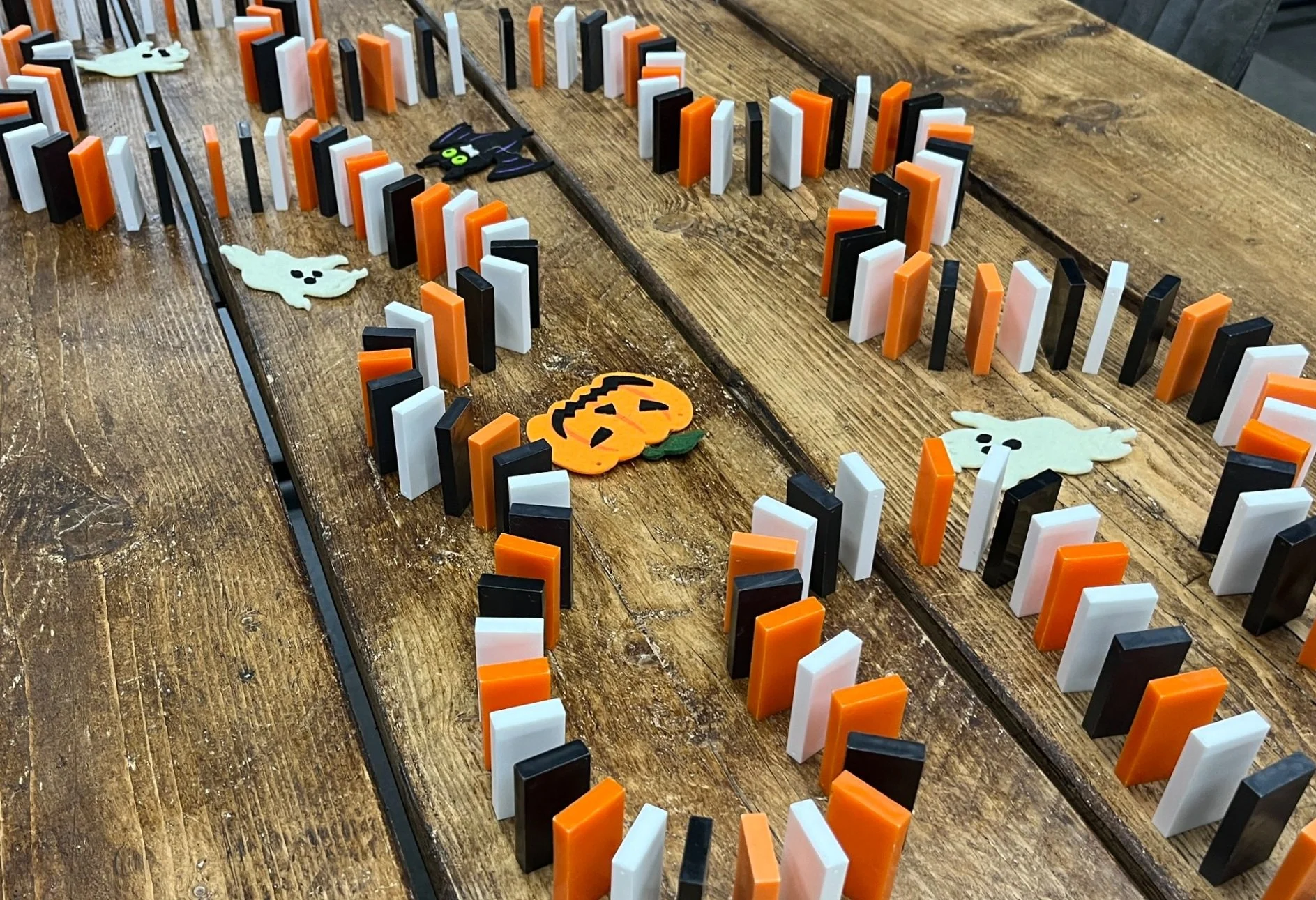 White, orange and black dominoes swirled around felt patches that are Halloween themed (Pumpkin, ghost and bat).