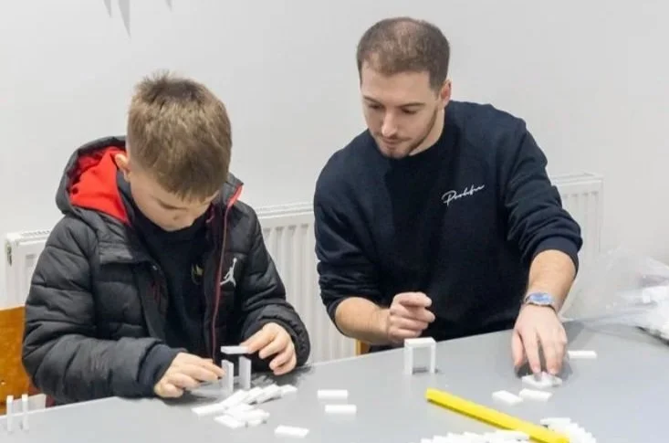 A man and a young boy working together on a domino project. 