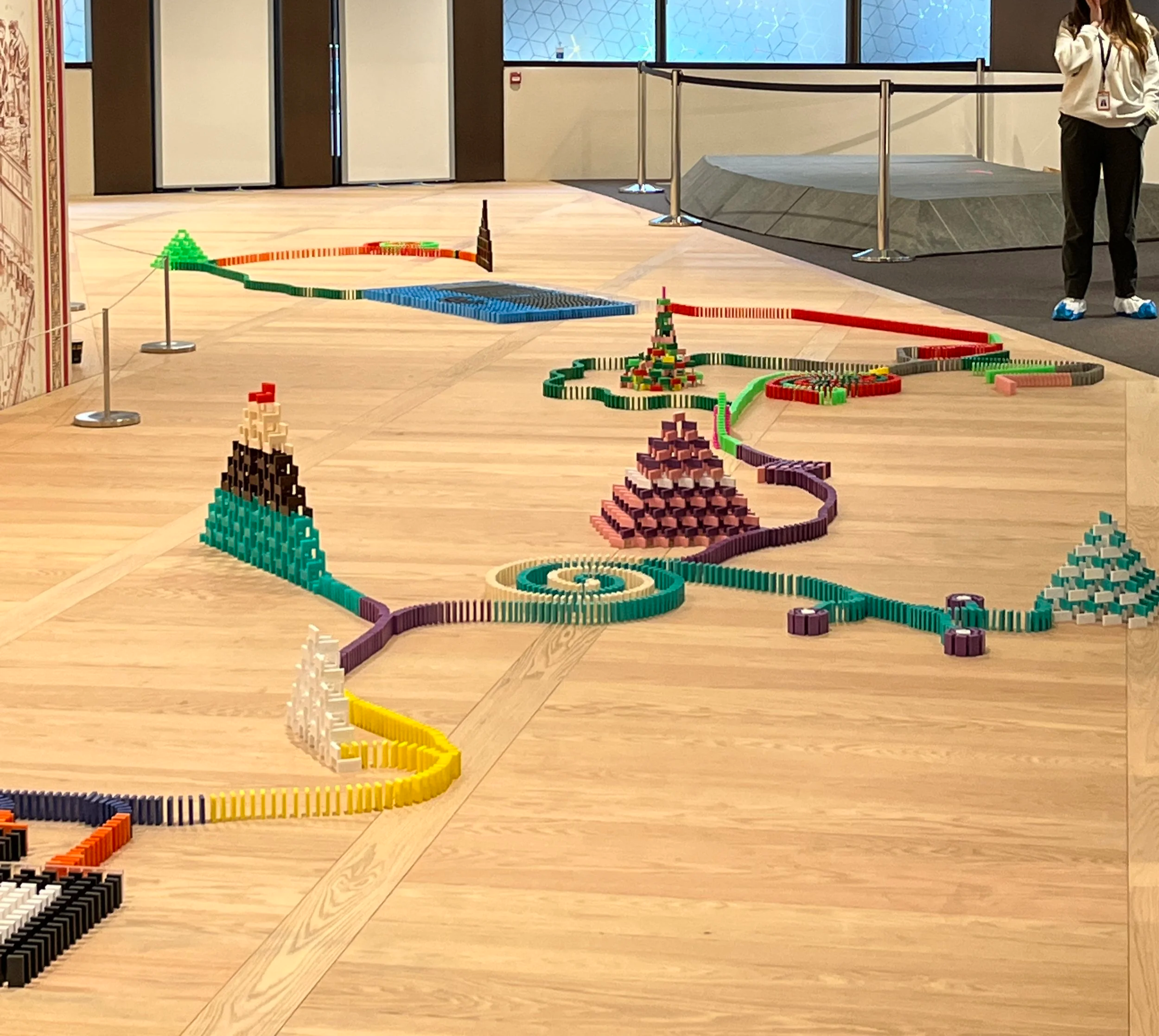 Colourful domino set arranged in a team building workshop upon a wooden floor.