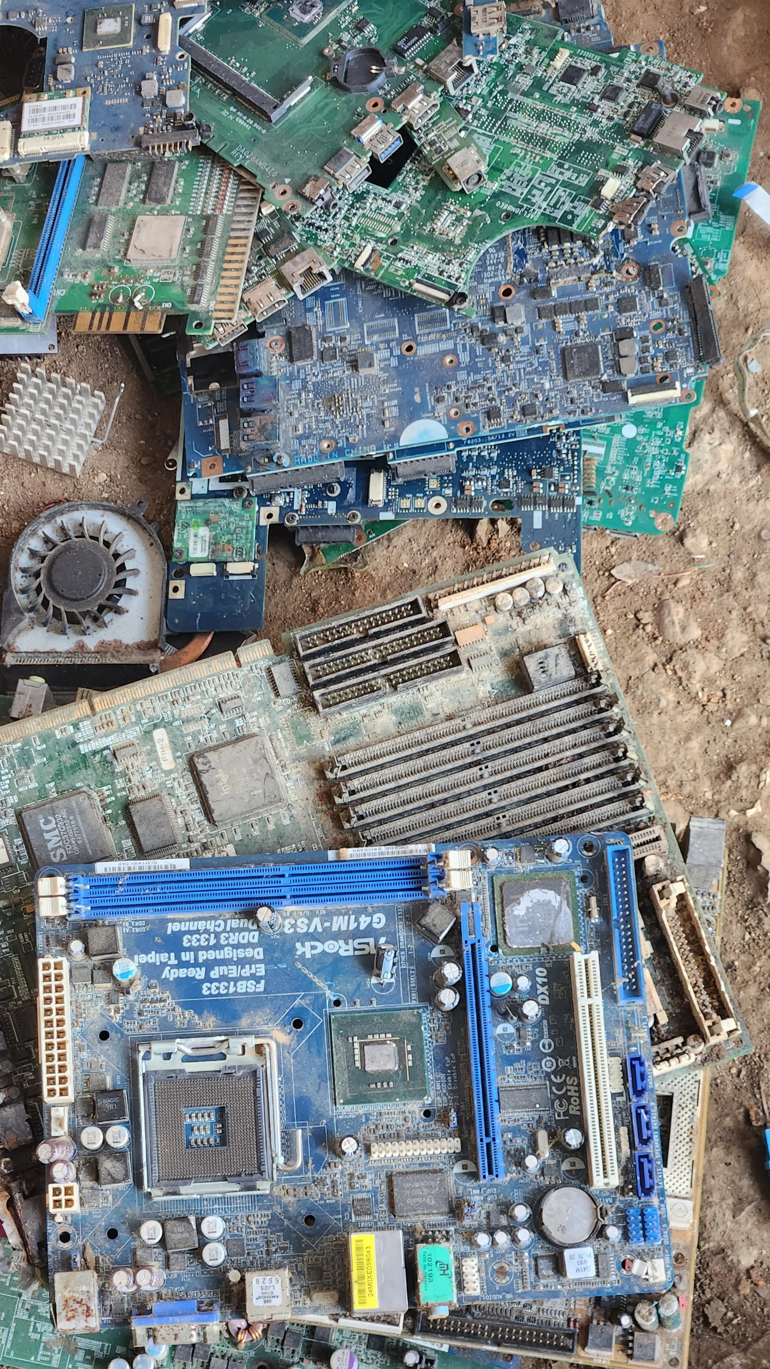 Chatarra informática con varias placas base y componentes electrónicos en tierra