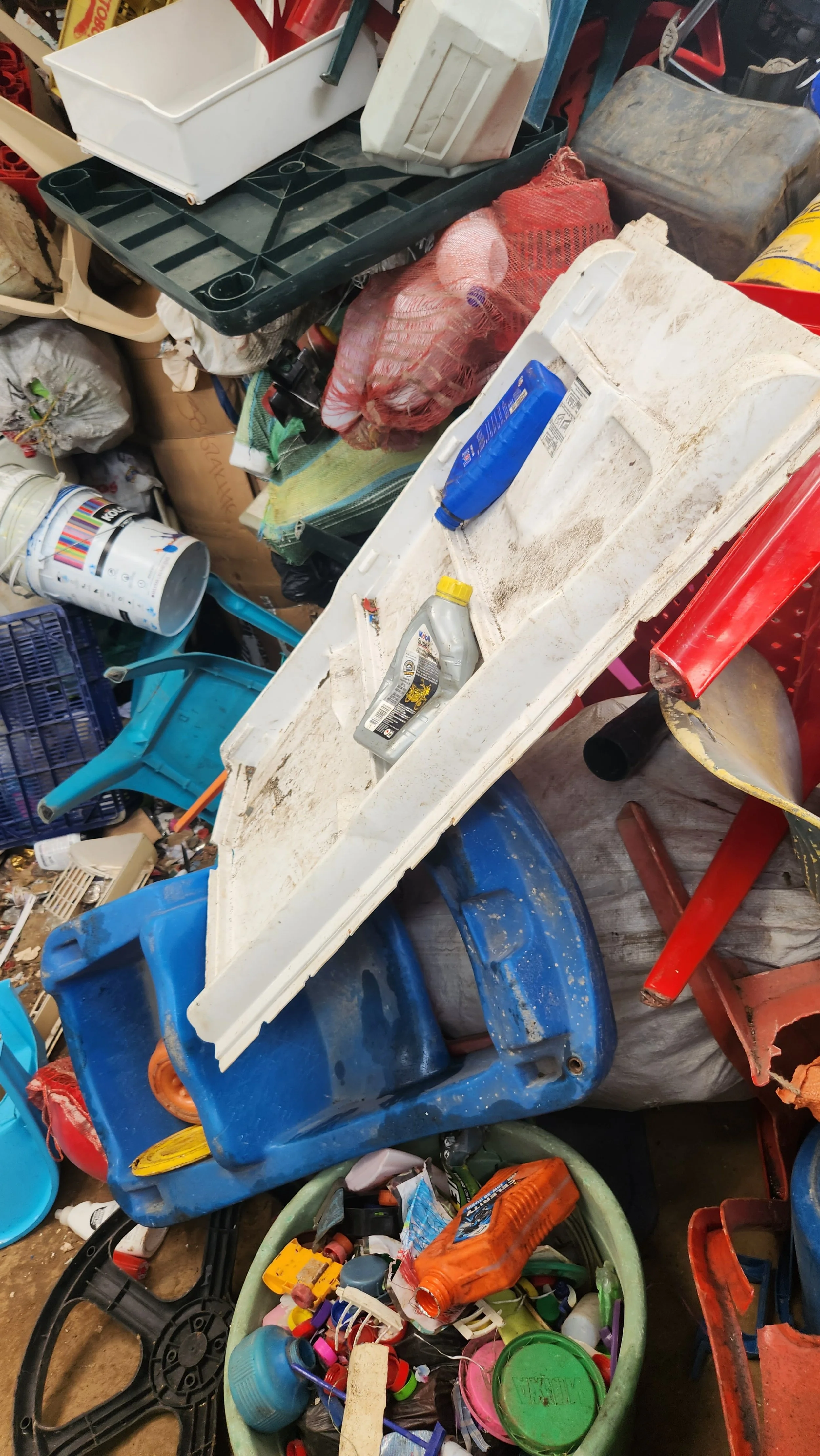 Acumulación de residuos reciclables, incluyendo botellas, envases y cubetas de plástico en desorden.