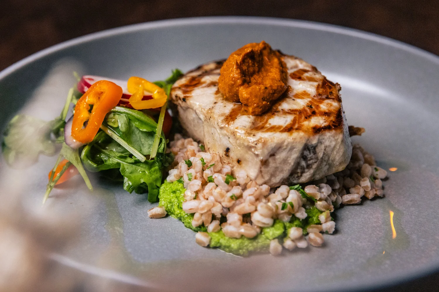 Grilled fish with a red pepper sauce on farro and a green purée